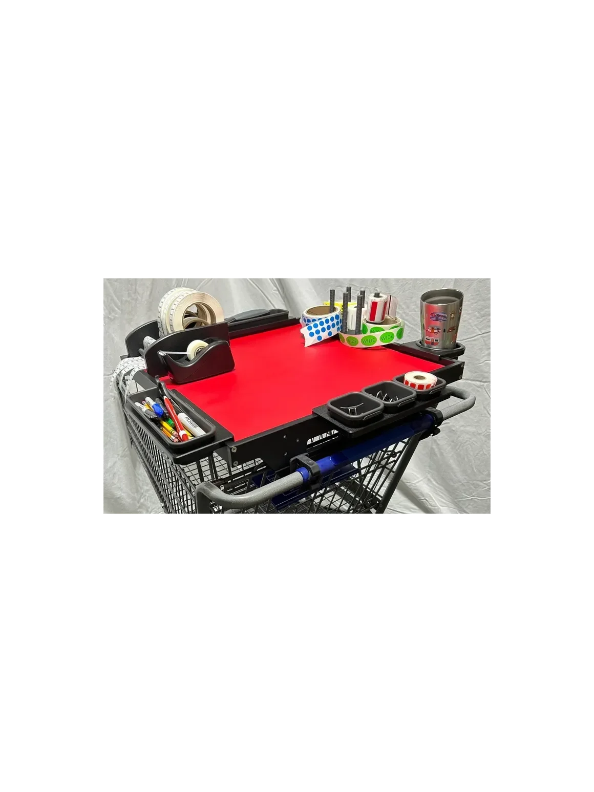 A shopping cart with a red platform tray filled with various office supplies, including tape dispensers, pens, markers, washi tapes, and a stainless steel tumbler.