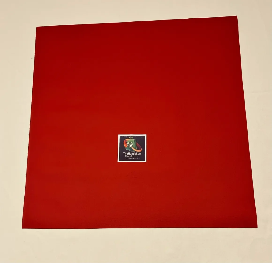 A large red sheet of paper with a small sticker in the center that says "TheHandyCart" and has a colorful logo.