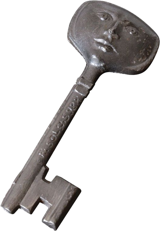 An antique metal key with a face carved into the head, showing eyes, nose, and lips.