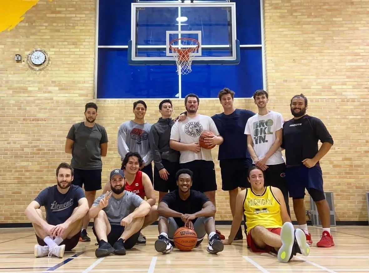 Group of young adults on a basketball court, posing for a photo after playing.