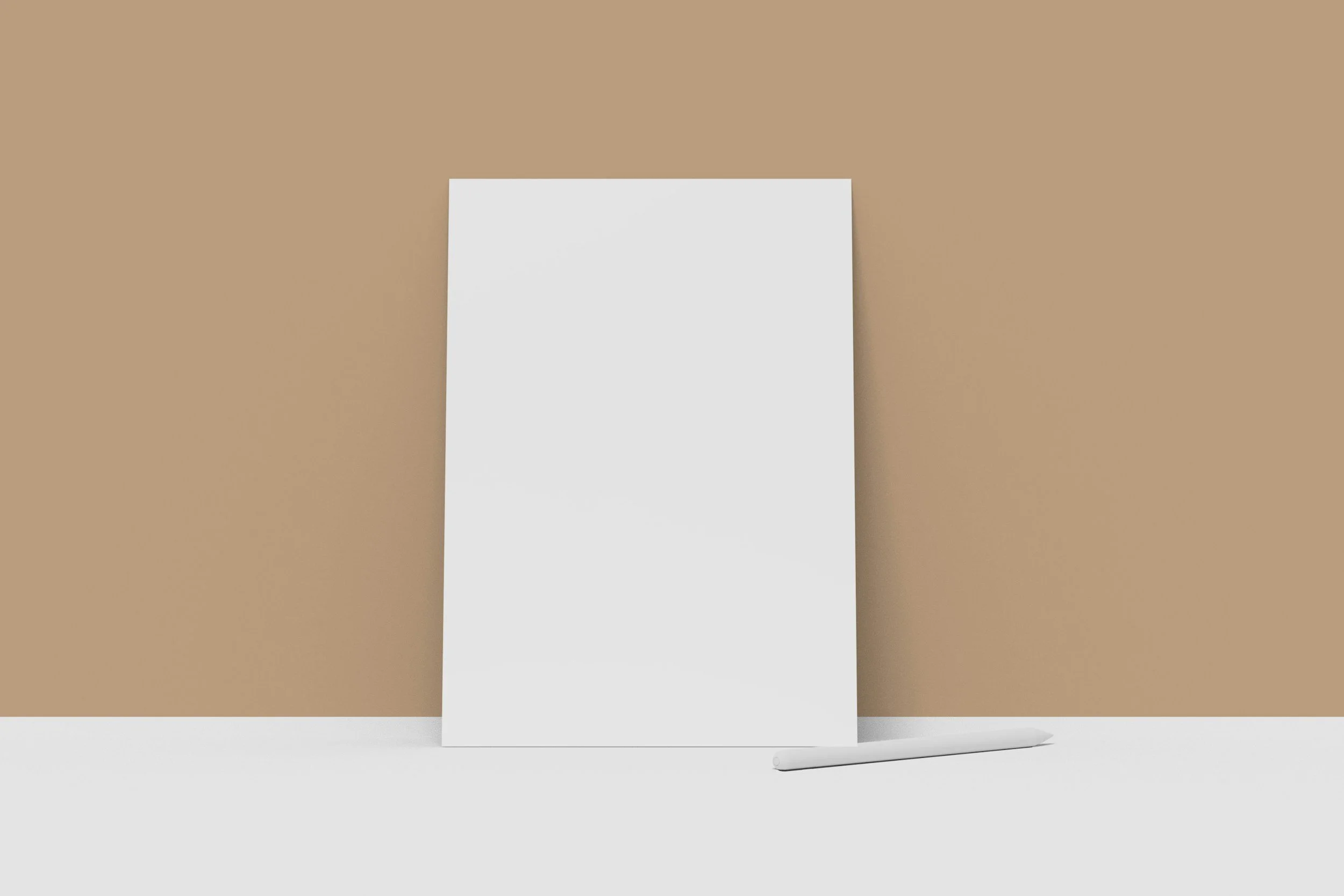 A blank white board leaning against a beige wall on a white surface with a tray or roller brush lying on the surface in front of it.