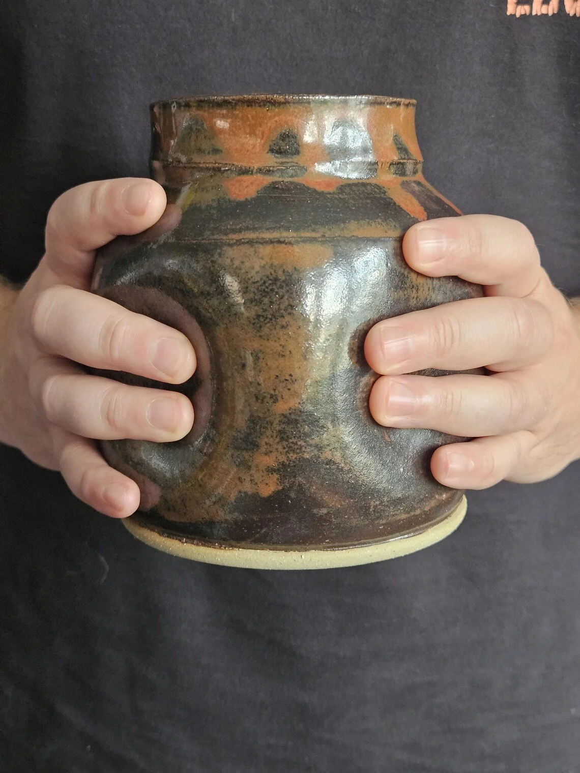 Schiprek Ceramics jar was modified after being wheel thrown by lightly squeezing with both hands around the piece. Dark red glaze with red drip, fired to cone 6. About 5.5" tall, 5.5" wide.