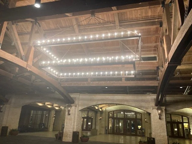 Lighting fixture shaped like a diamond hanging from a wooden ceiling in an industrial-style building.