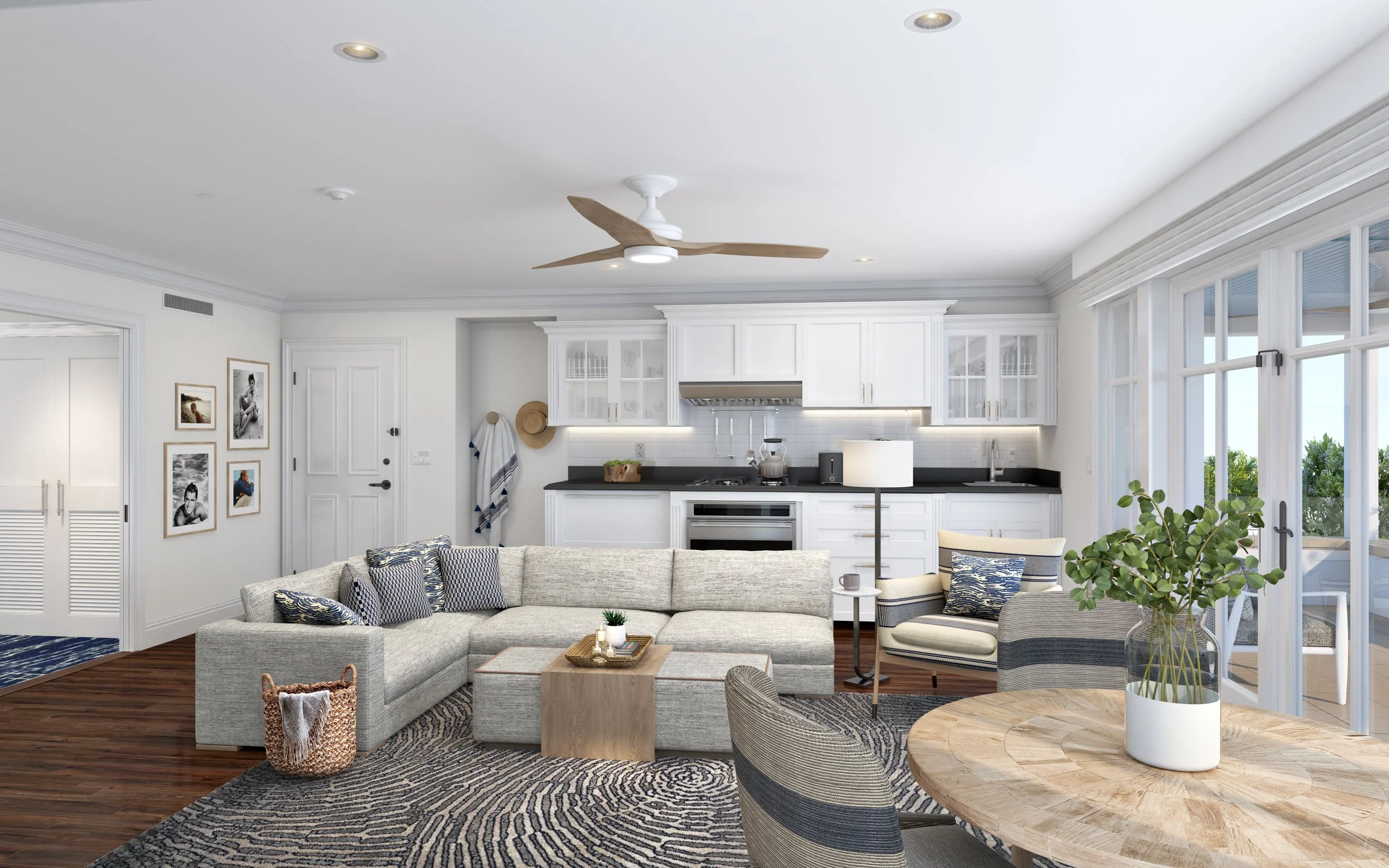 Bright living room with white kitchen, gray sectional sofa, wooden coffee table, striped armchair, large window with sliding doors, and indoor plants.