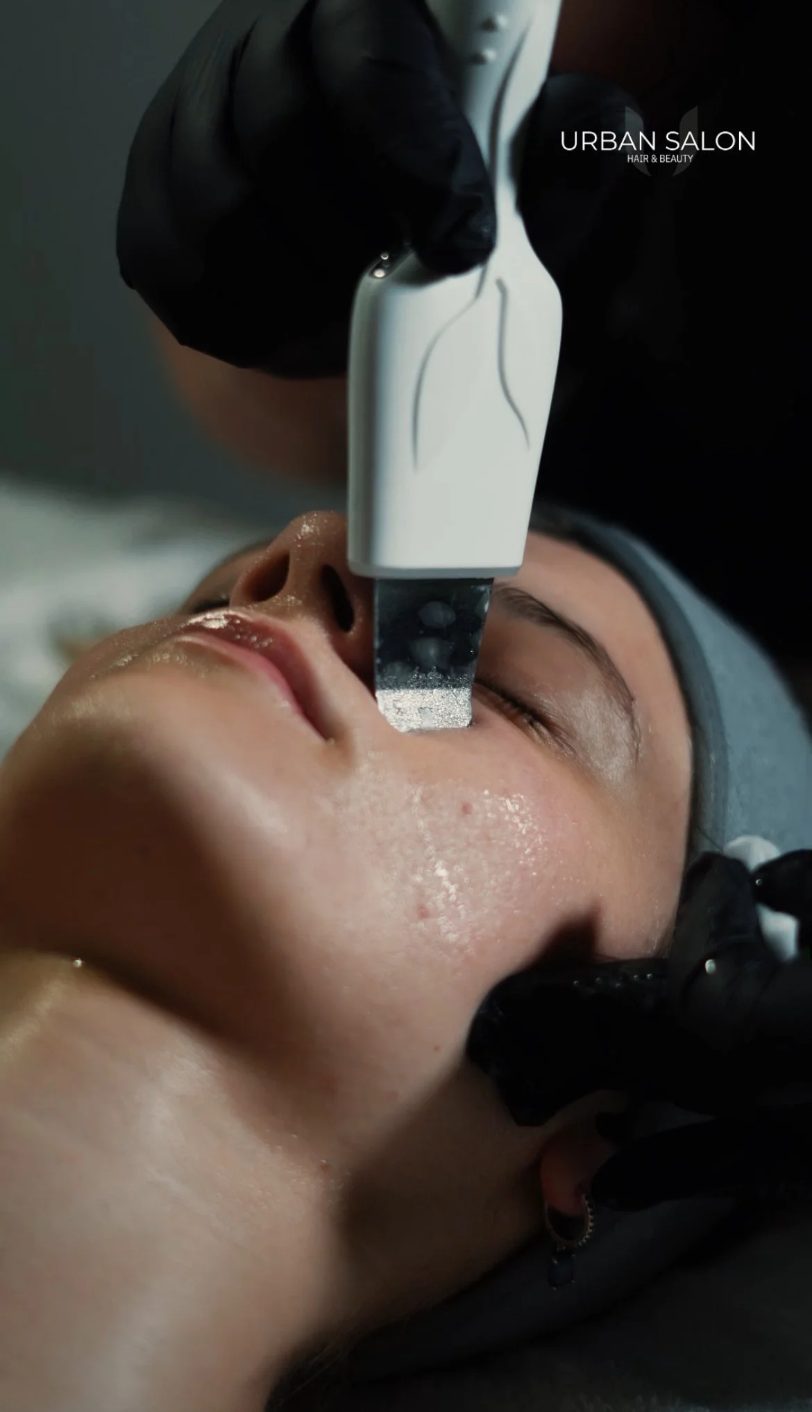 A person receiving a facial treatment with a specialized device at Urban Salon Hair & Beauty.