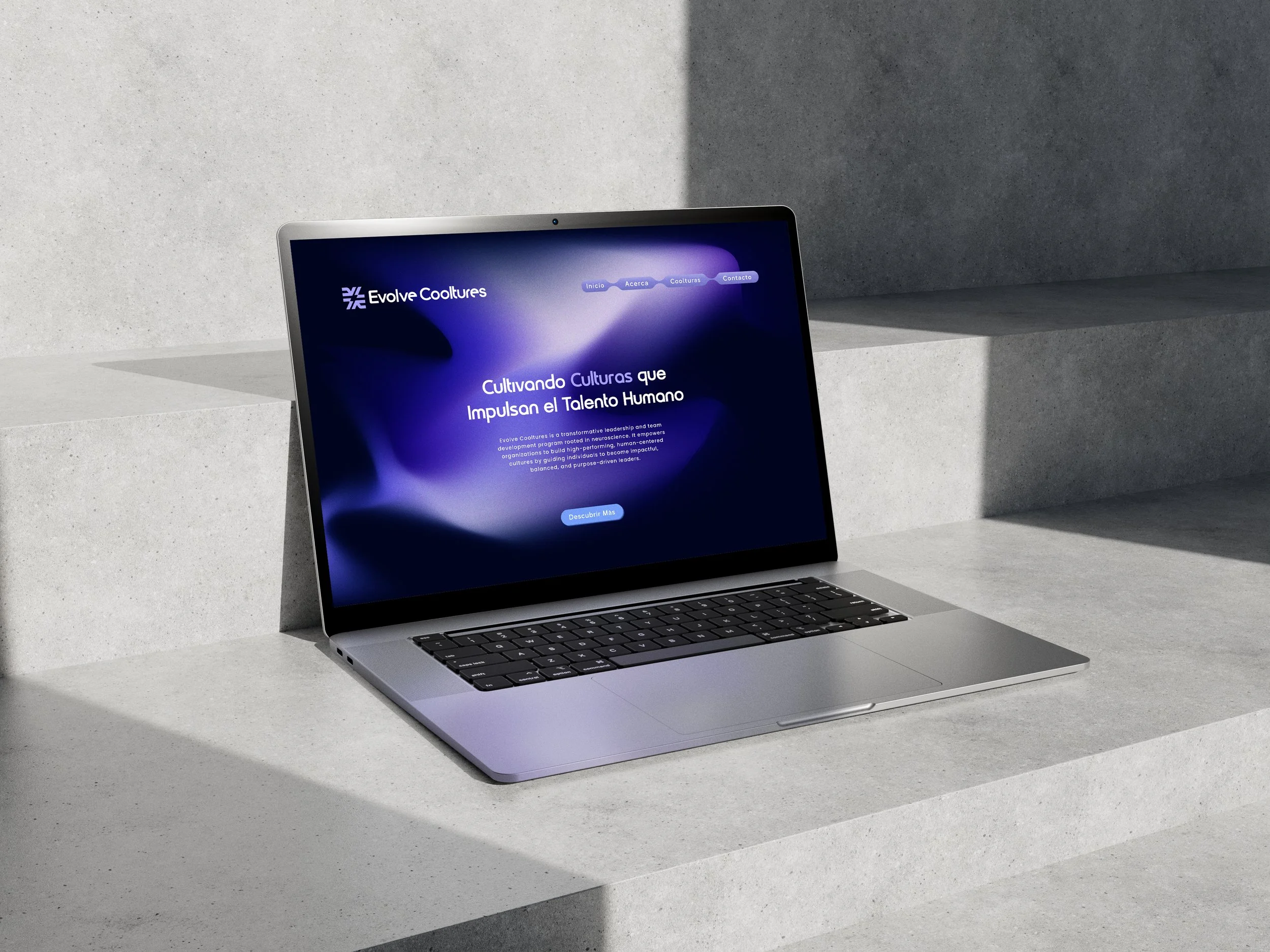 A laptop displaying a website titled Evolve Cooltures, placed on a minimalist concrete surface with geometric steps.