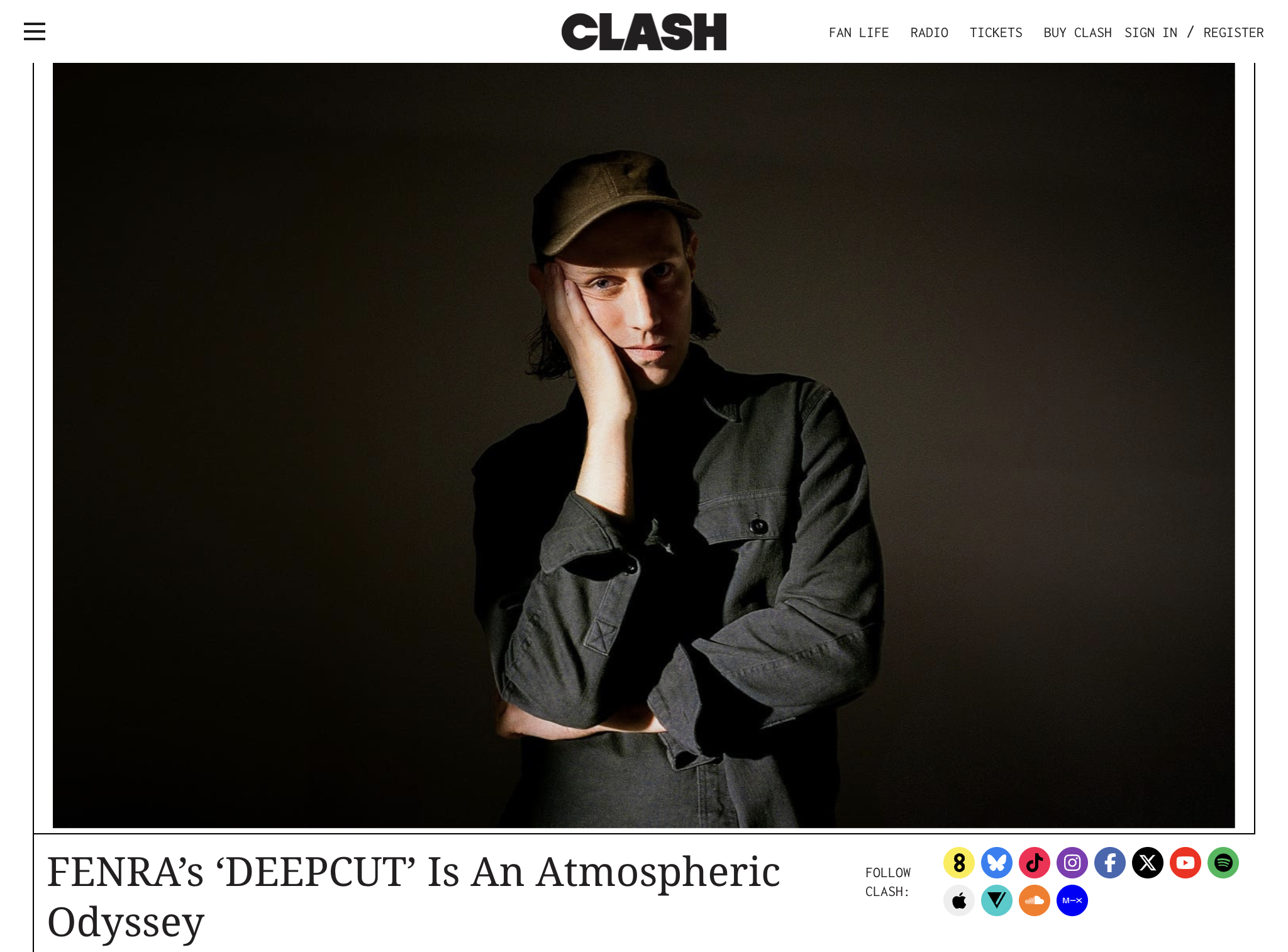 Webpage image of Clash Magazine showing electronic musician and producer, FNERA, standing in a photo studio standing in a dark, button up shirt and cap.