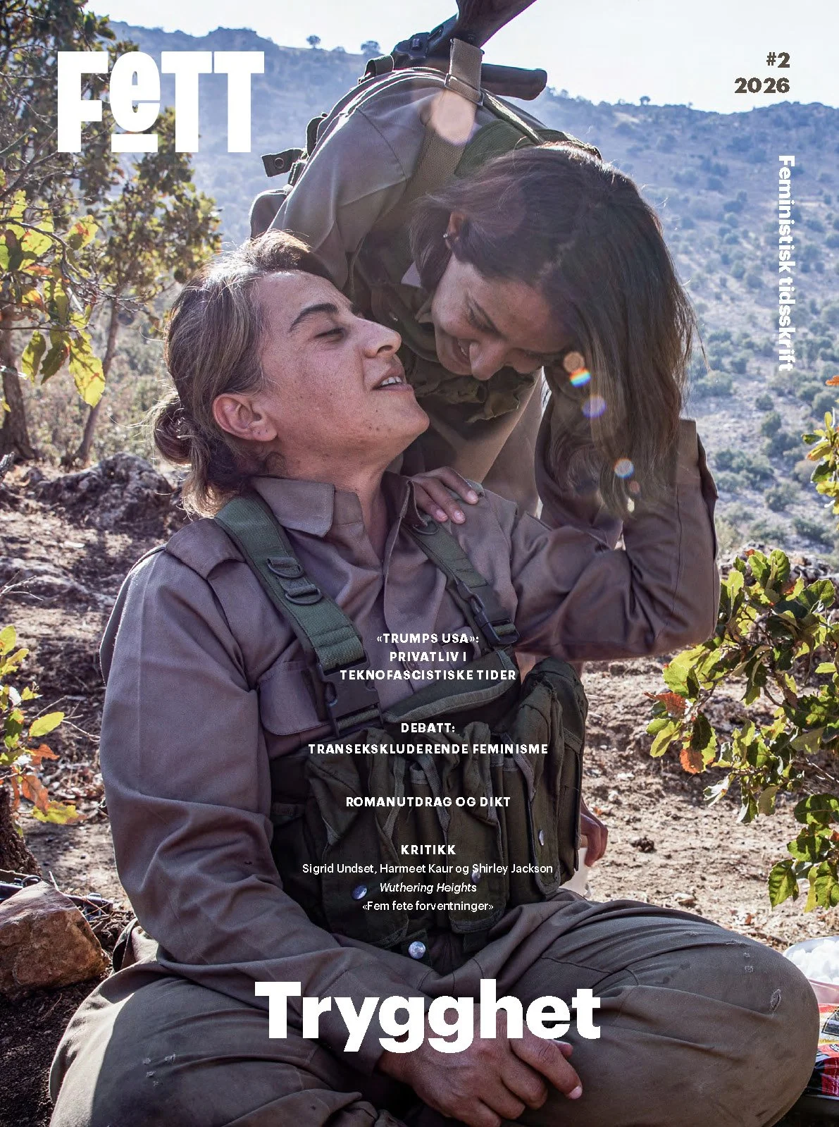 Forsidebilde til Fett #2/26 TRYGGHET. To kvinnelige kurdistanske soldater som smiler mot hverandre i naturomgivelser. 