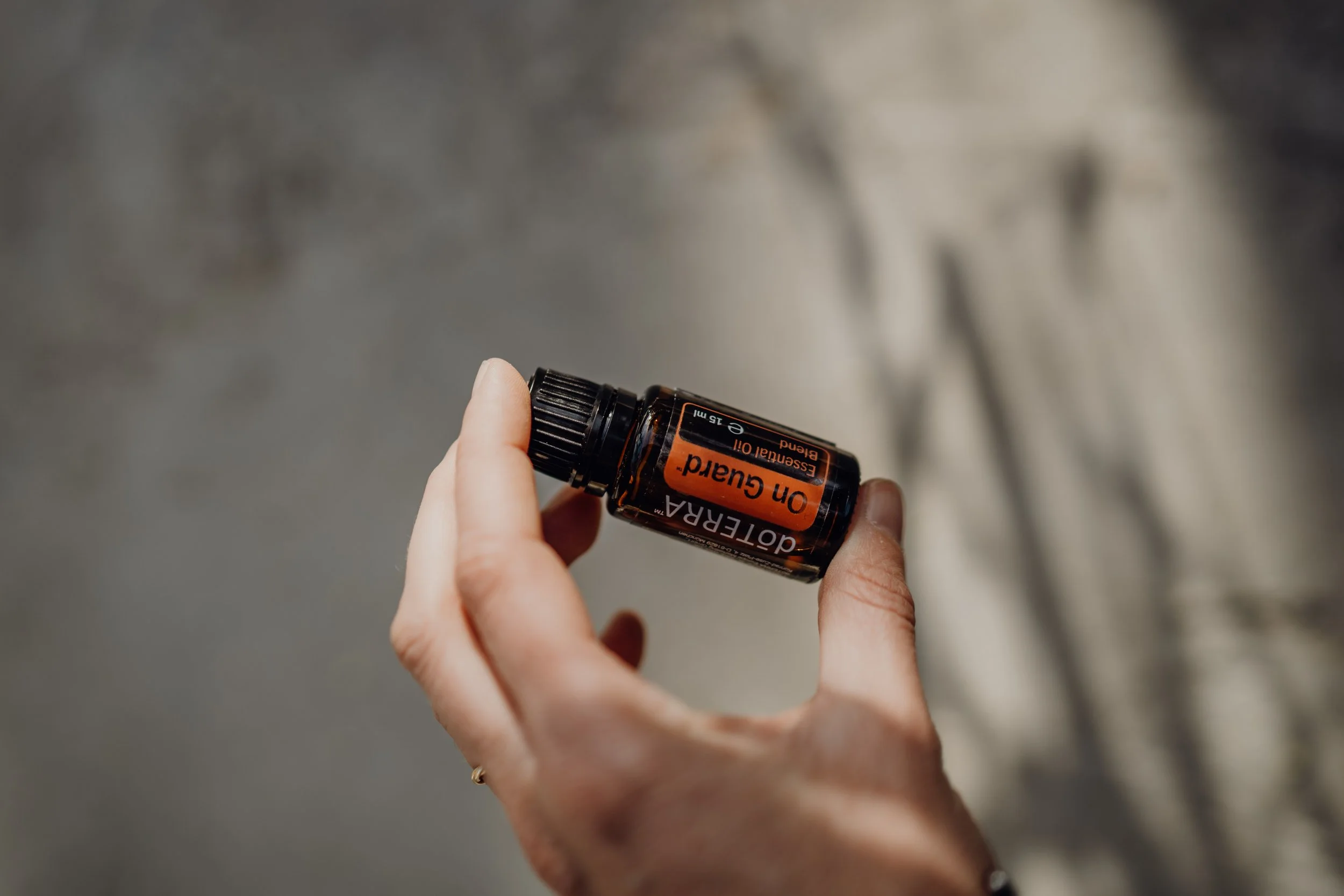 Hand hält eine Flasche mit ätherischem Öl, beschriftet mit 'on Guard'.