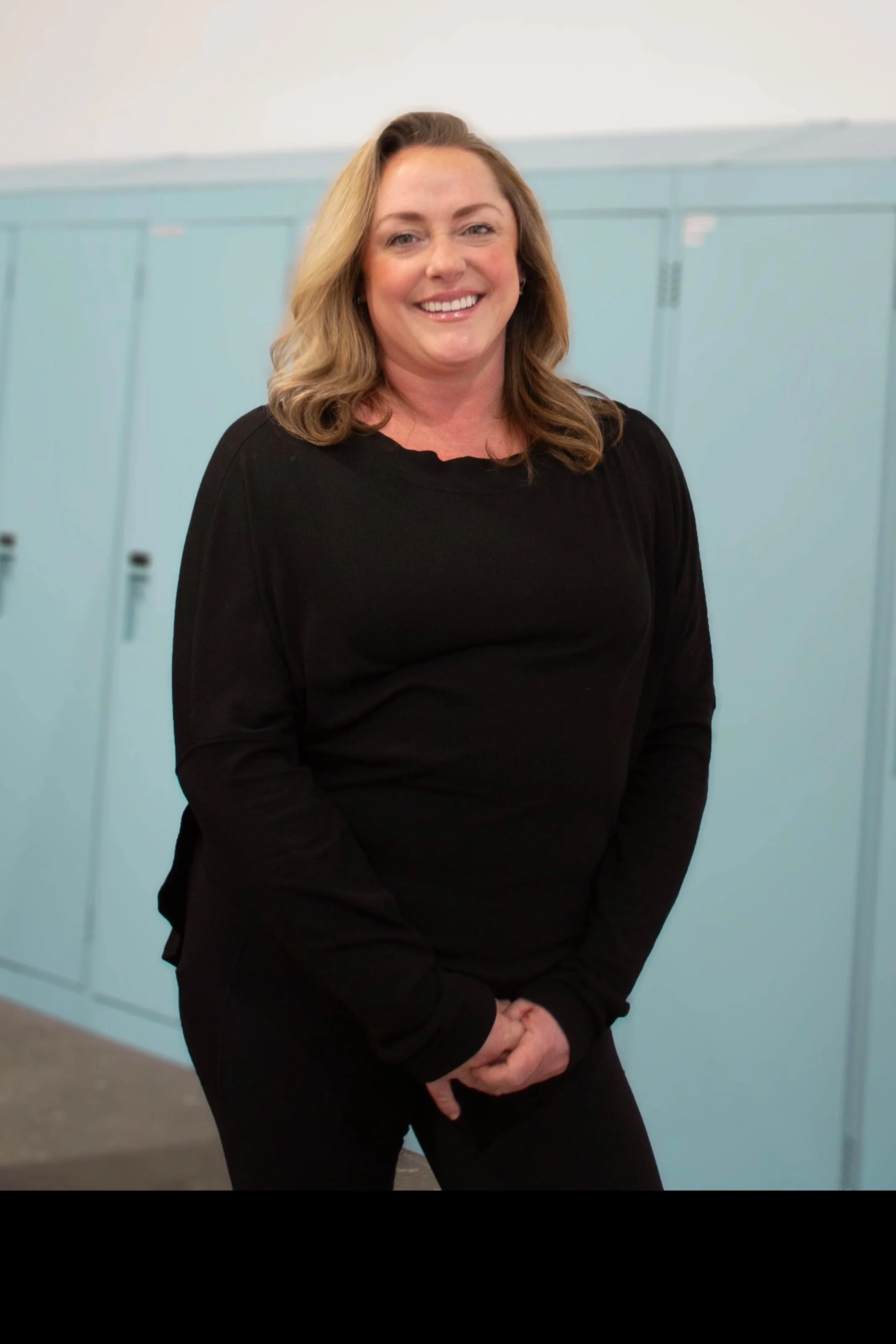 Smiling woman with blonde hair standing in front of light blue lockers.
