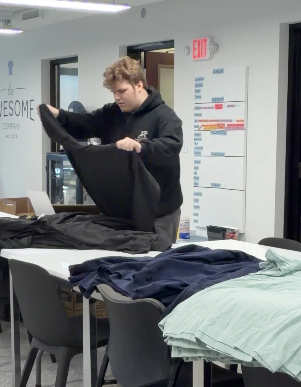 Team member preparing custom shirts in production space.
