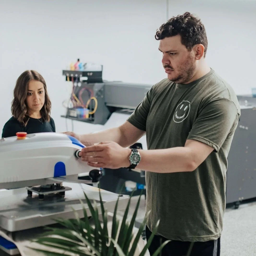 Team member carefully heat pressing a transfer to a t-shirt.