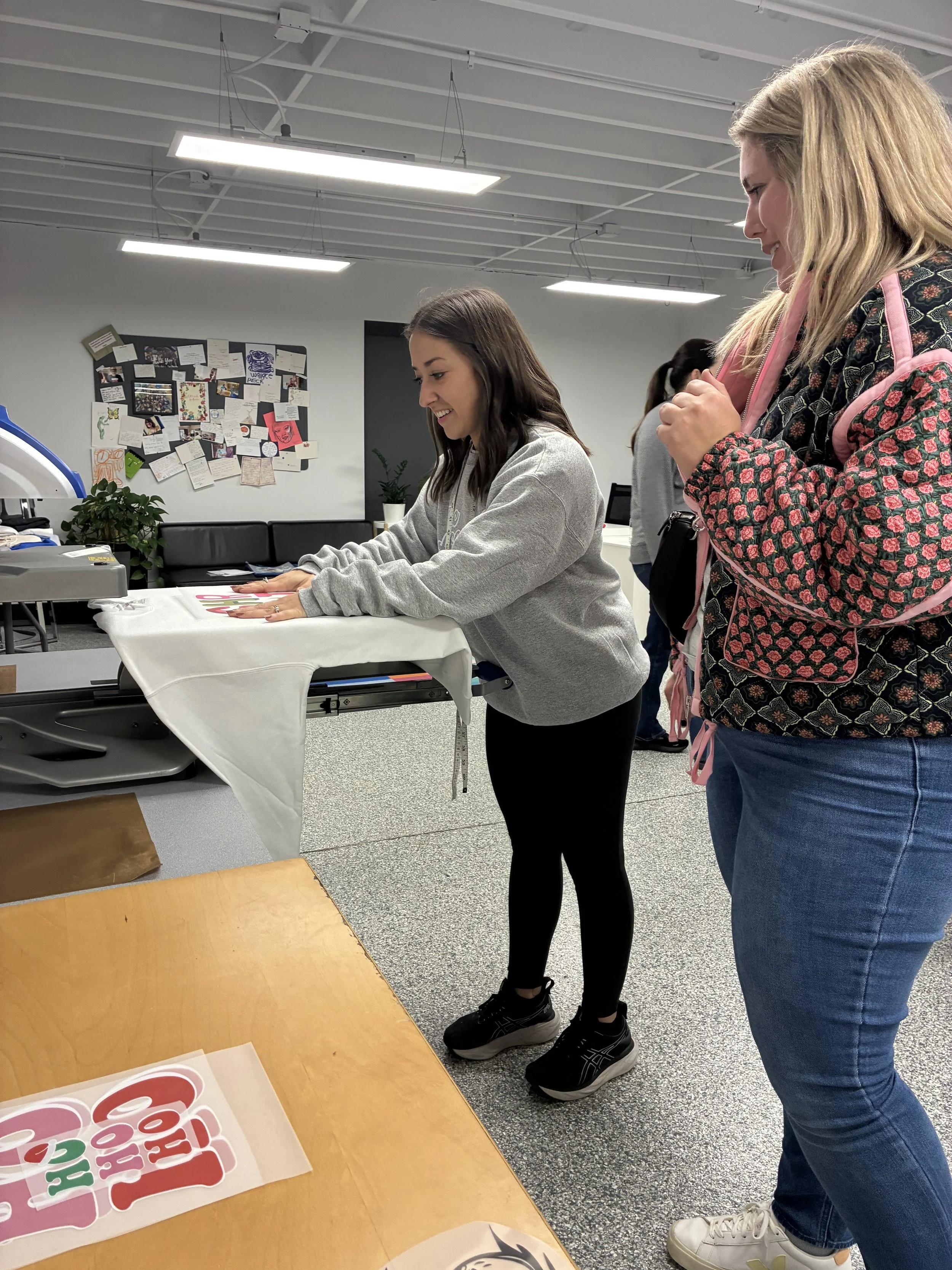 Guests heat pressing custom designs onto apparel during our 2025 Holiday themed print party.
