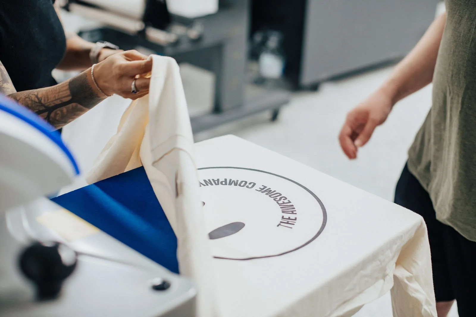 People folding a tote bag with the logo 'THE AVISOUNE COMPANY' printed on it