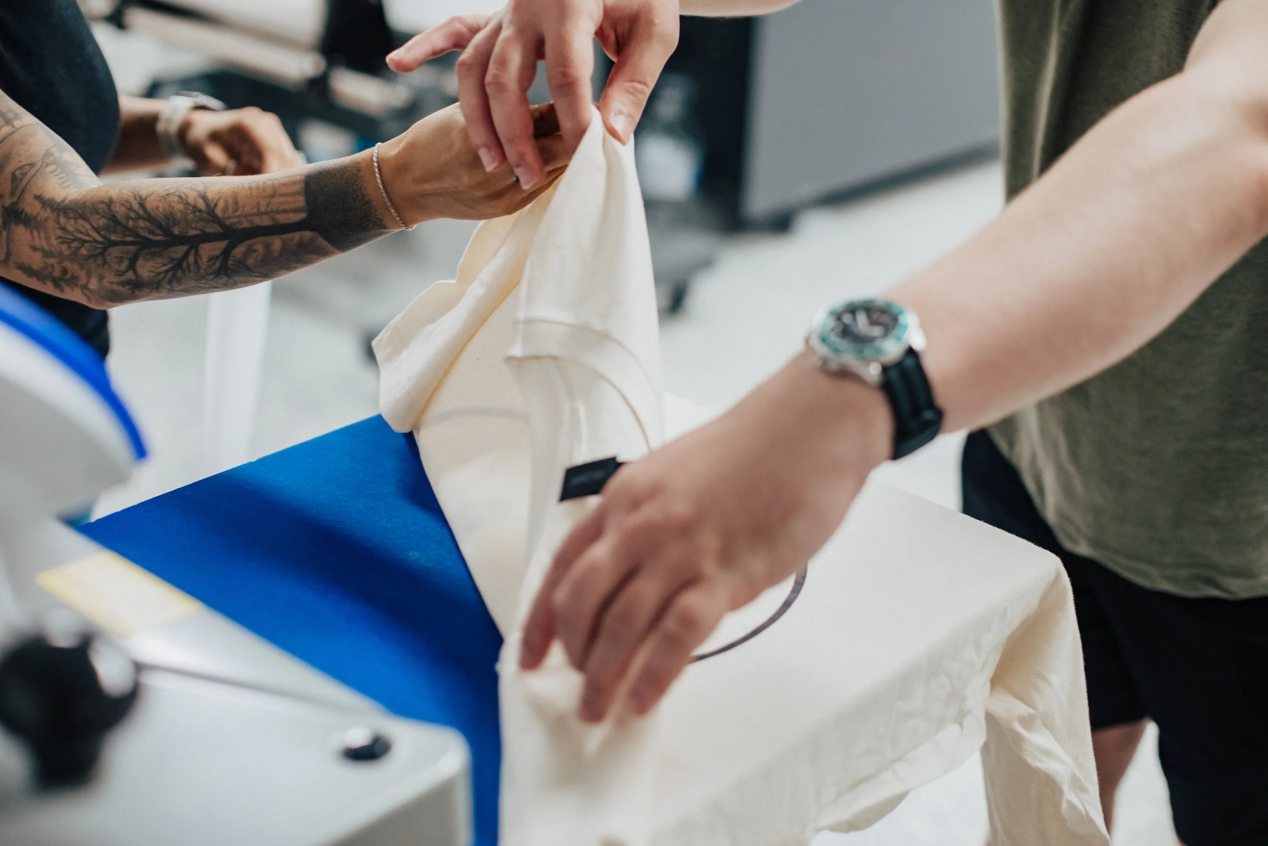 Employees removing a freshly printed shirt from the heat press.