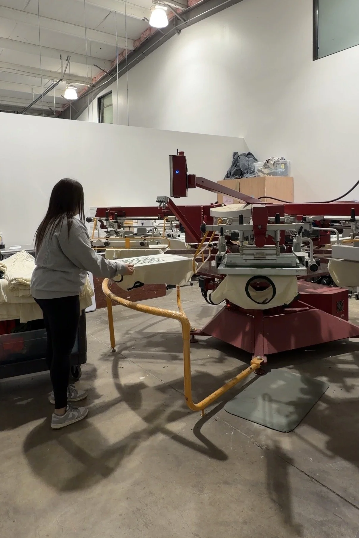 Employee screen printing an order of t-shirts.