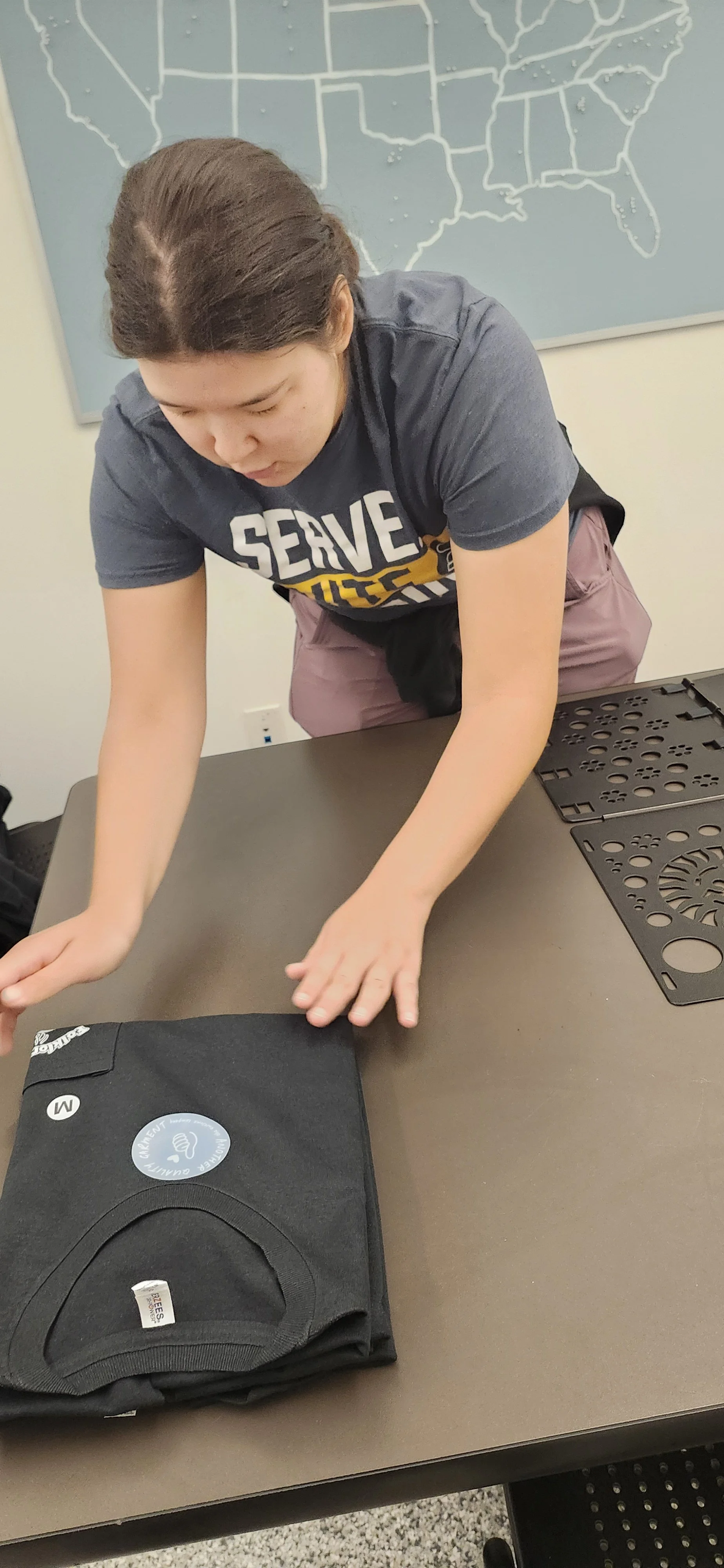 Team member inspecting freshly printed shirts for quality.