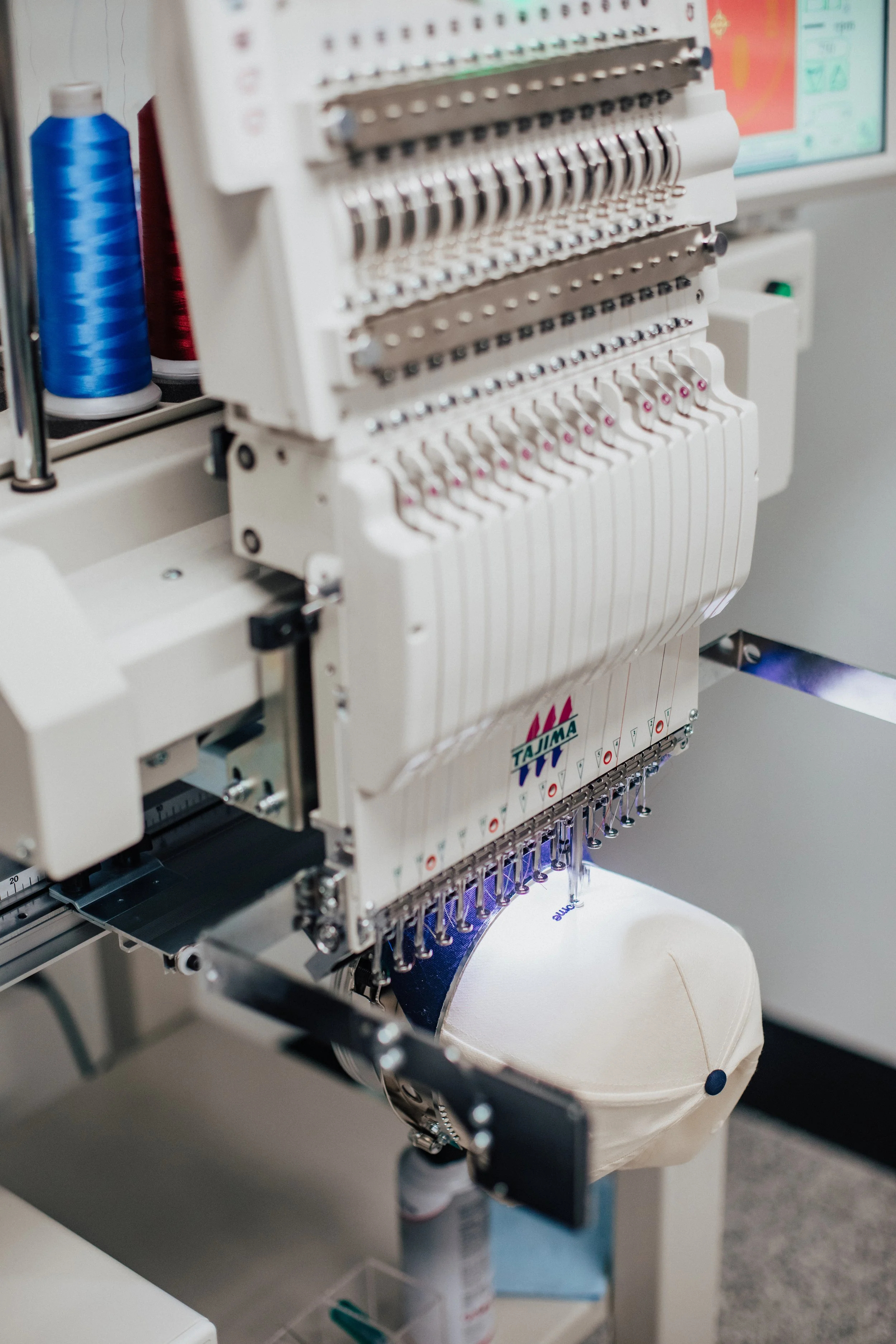 Embroidery machine in a sewing room, embroidering a hat.