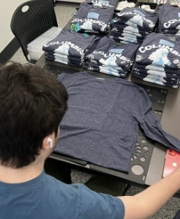 Person viewing stacks of folded shirts on a table.