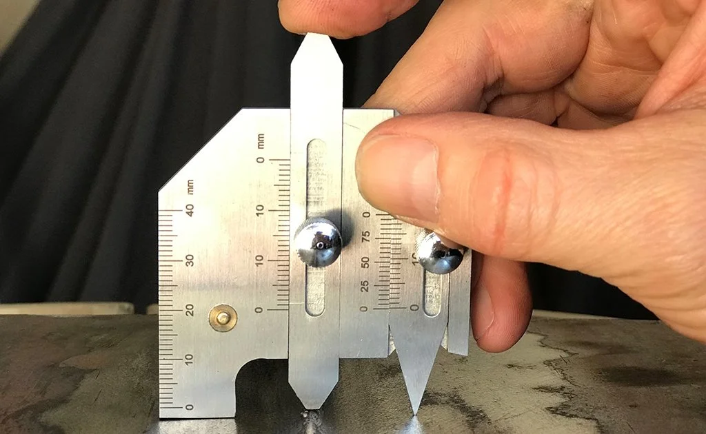 Person using a metal angle gauge to measure a metal surface.