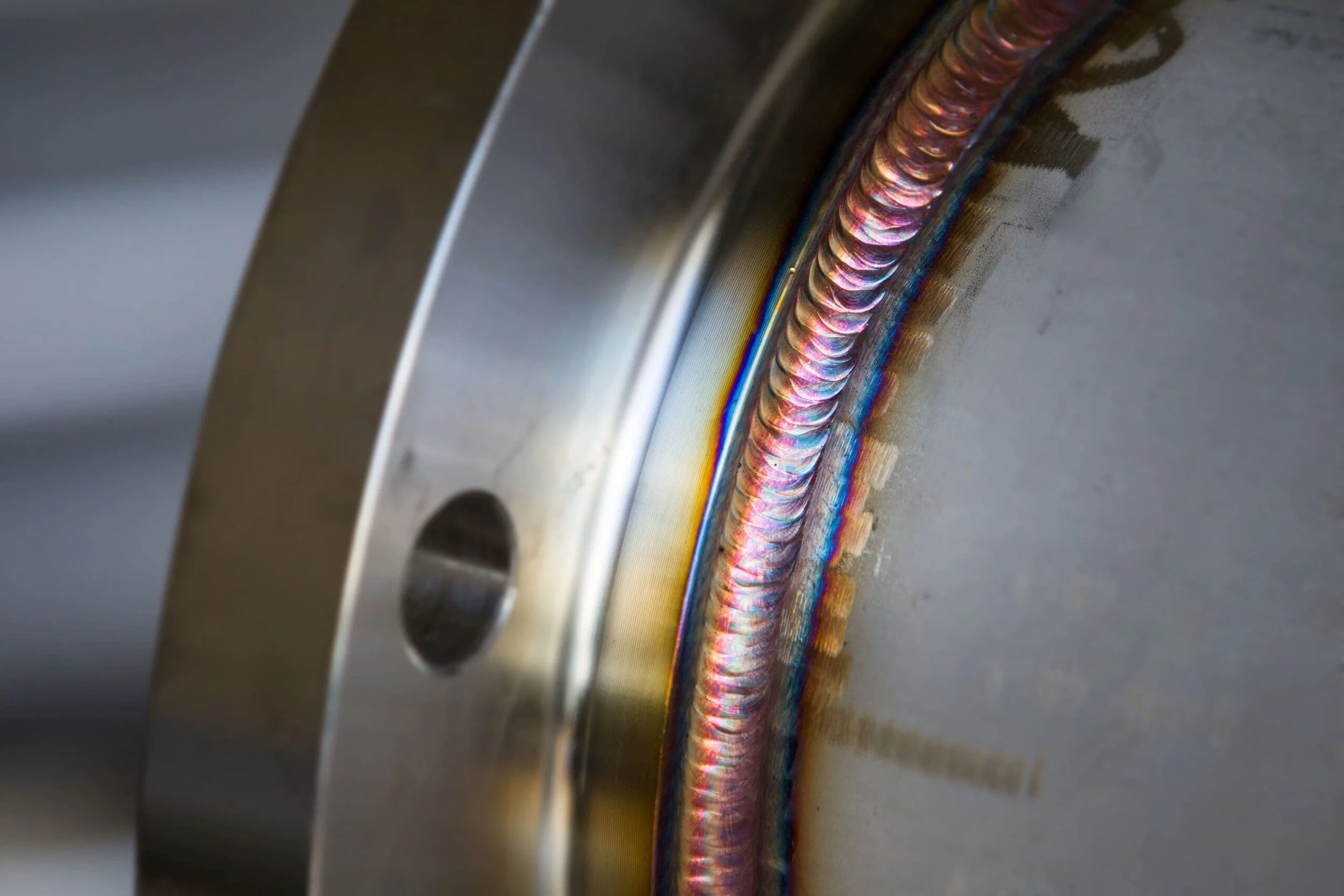 Close-up of a welded metal seam showing colorful heat-affected zone. Welding Inspection, visual testing, weld testing, welding qualification