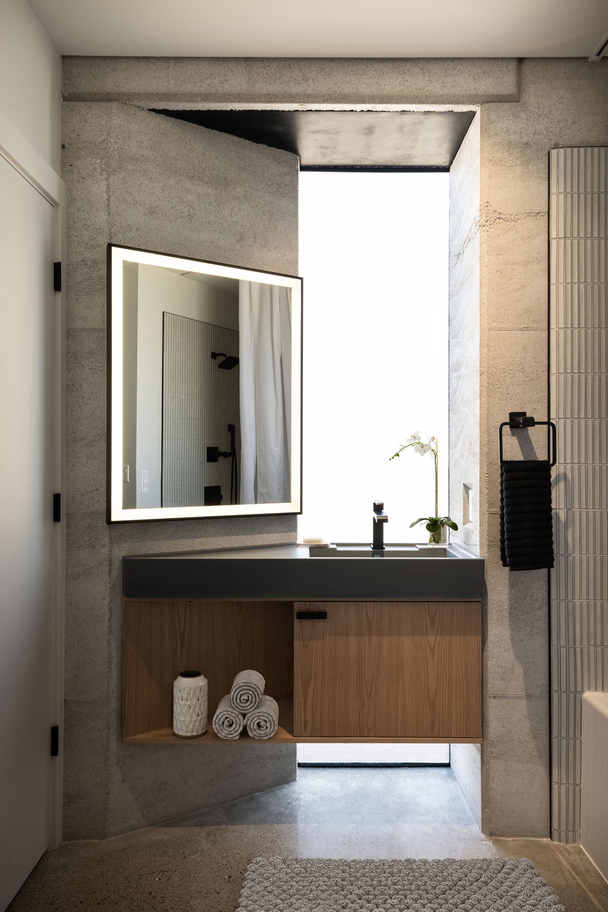 Minimalist bathroom showing smooth stabilized Rammed Earth wall.