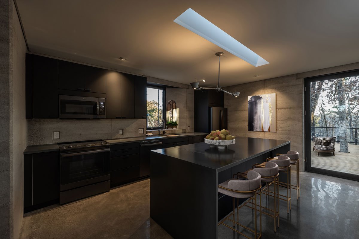Warm stone tones of Rammed Earth wall surrounding modern appliances.