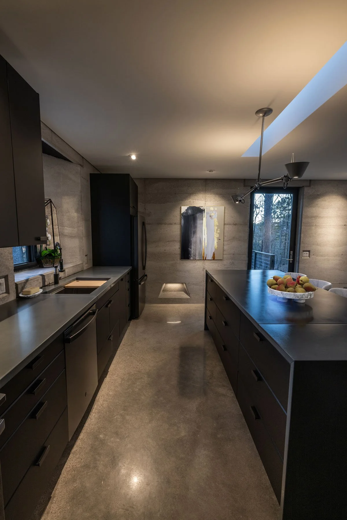 Recessed pathway lighting illuminating Rammed Earth kitchen wall.
