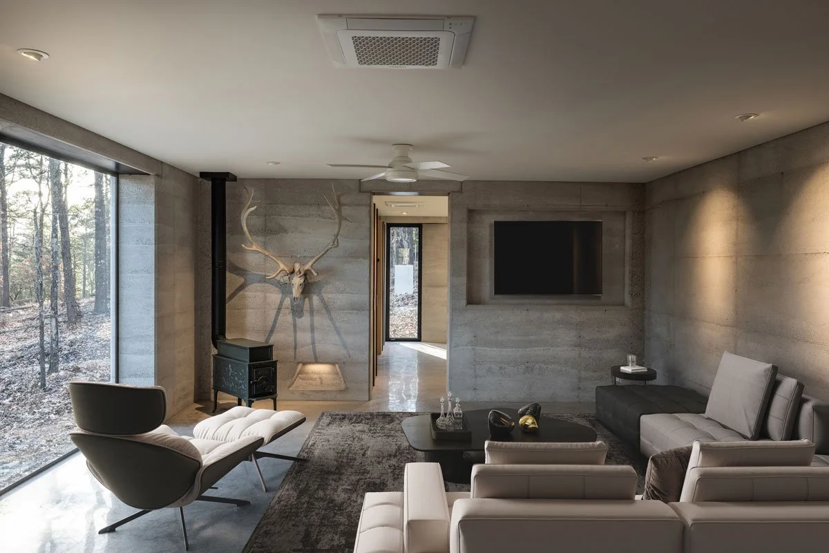 Cozy seating area framed by thick Rammed Earth walls and large windows.