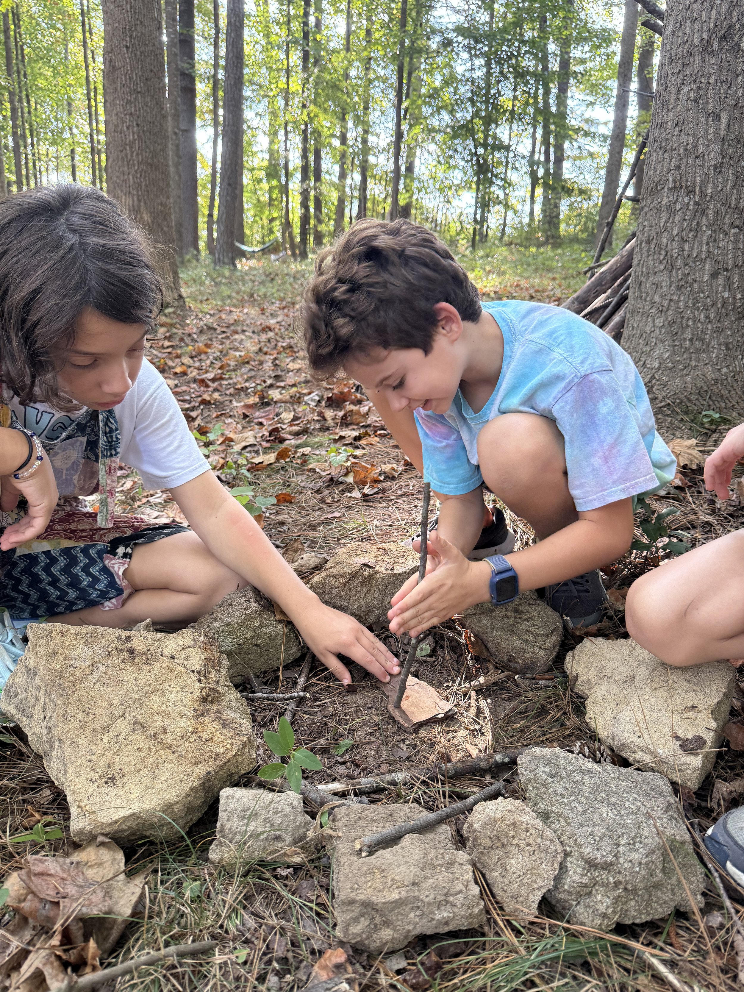 Children experimenting and learning primitive earthskills attempting to make fire by friction