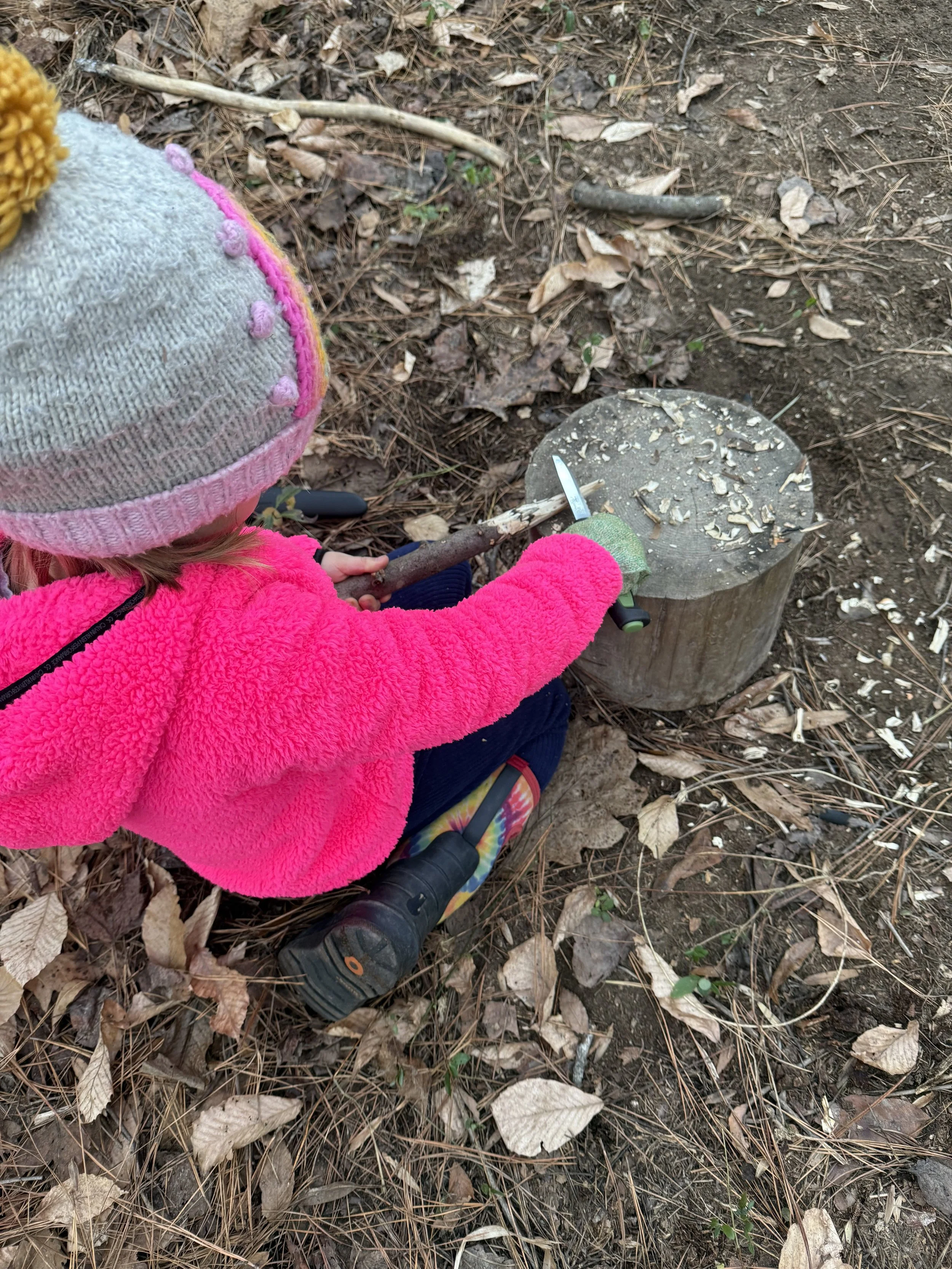 Child whittling a stick to learn wood carving and safe knife use