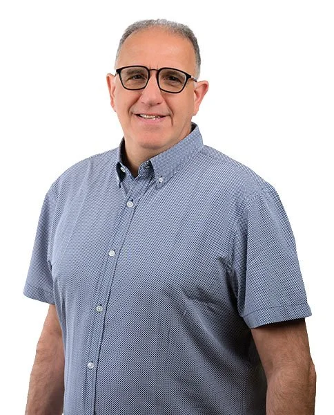 Portrait d'un homme portant une chemise à manches courtes, avec des lunettes, souriant, fond blanc.