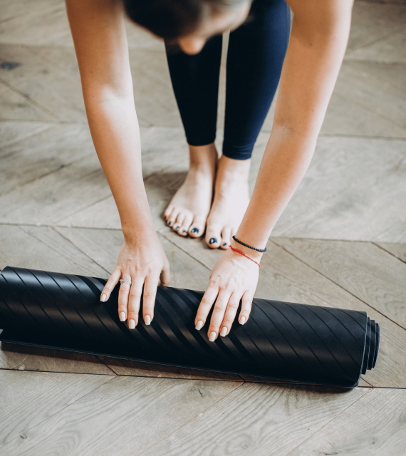 Person som rullar ut en yogamatta på golvet.