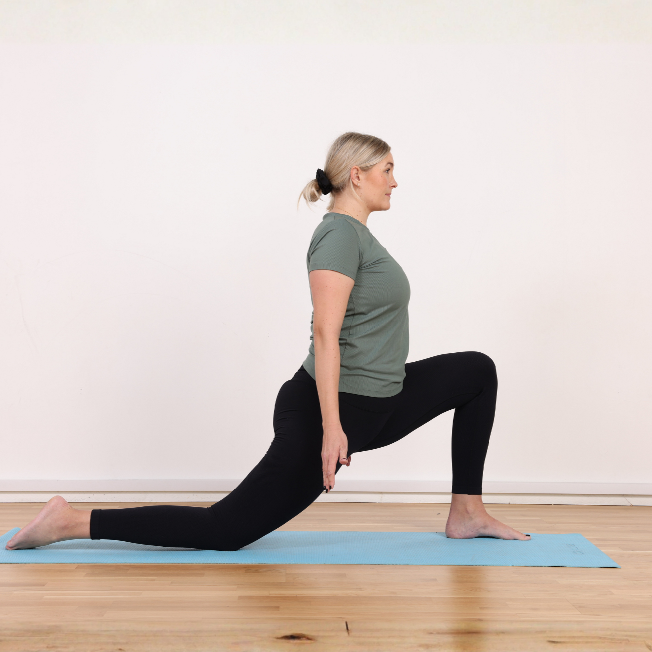 Kvinna i yoga-position på matta, utför lungeövning