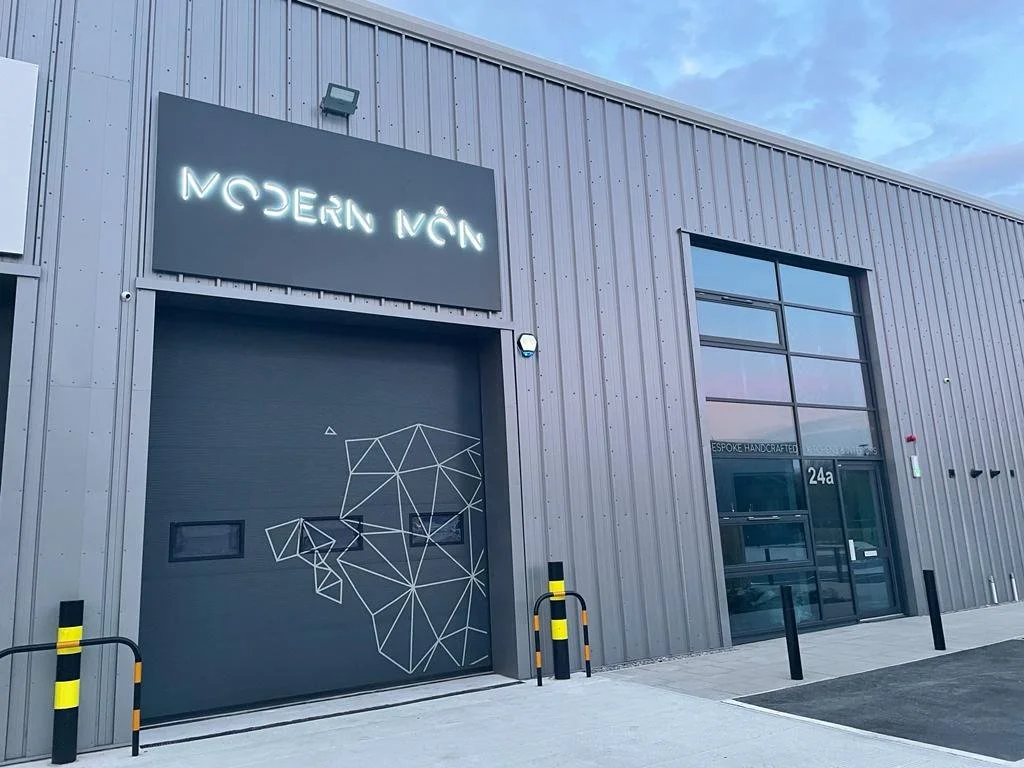 Industrial building with a sign that reads 'MODERN MÁR' and a geometric animal design on a garage door.