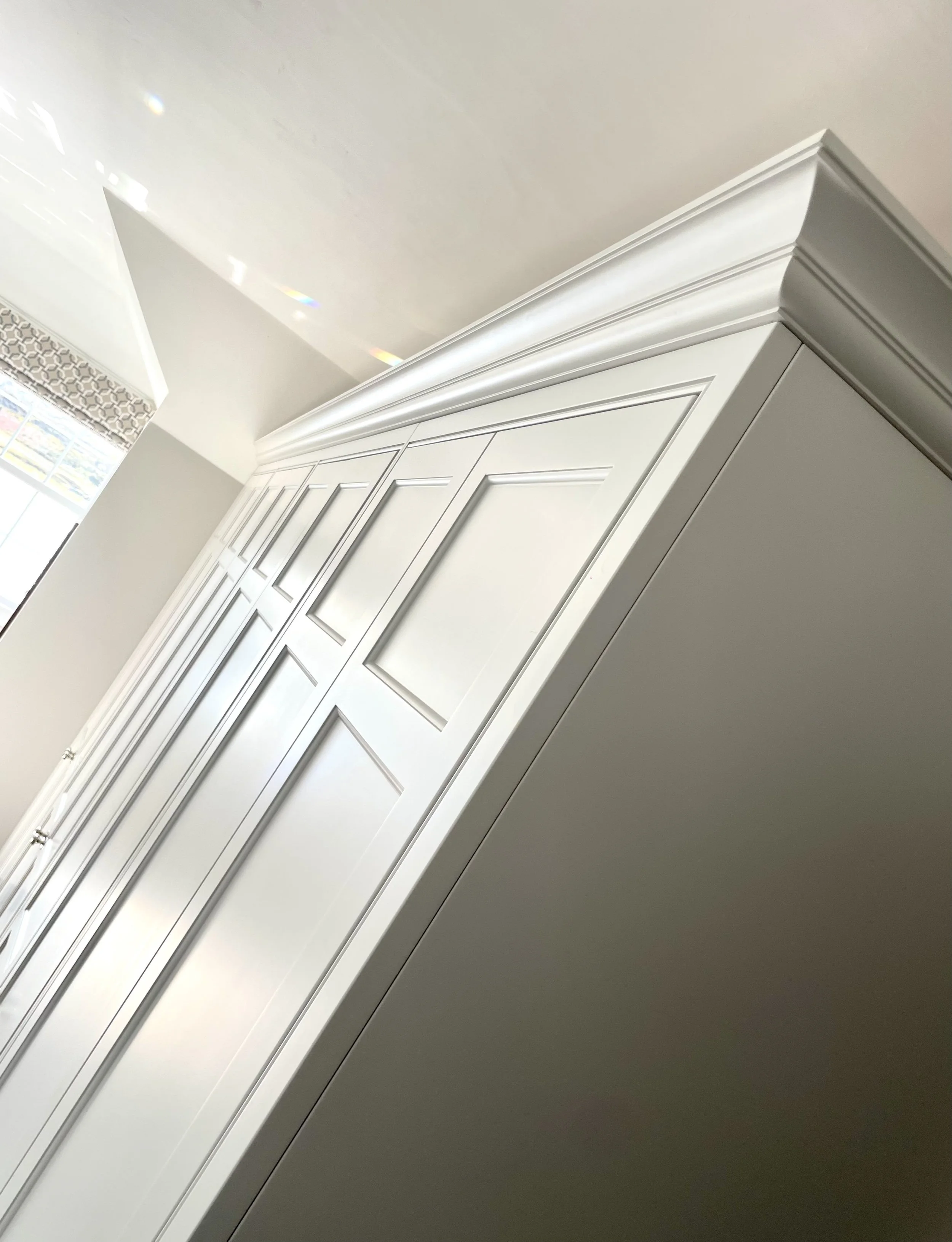 Close-up of a white cabinet with detailed crown molding in a well-lit room.