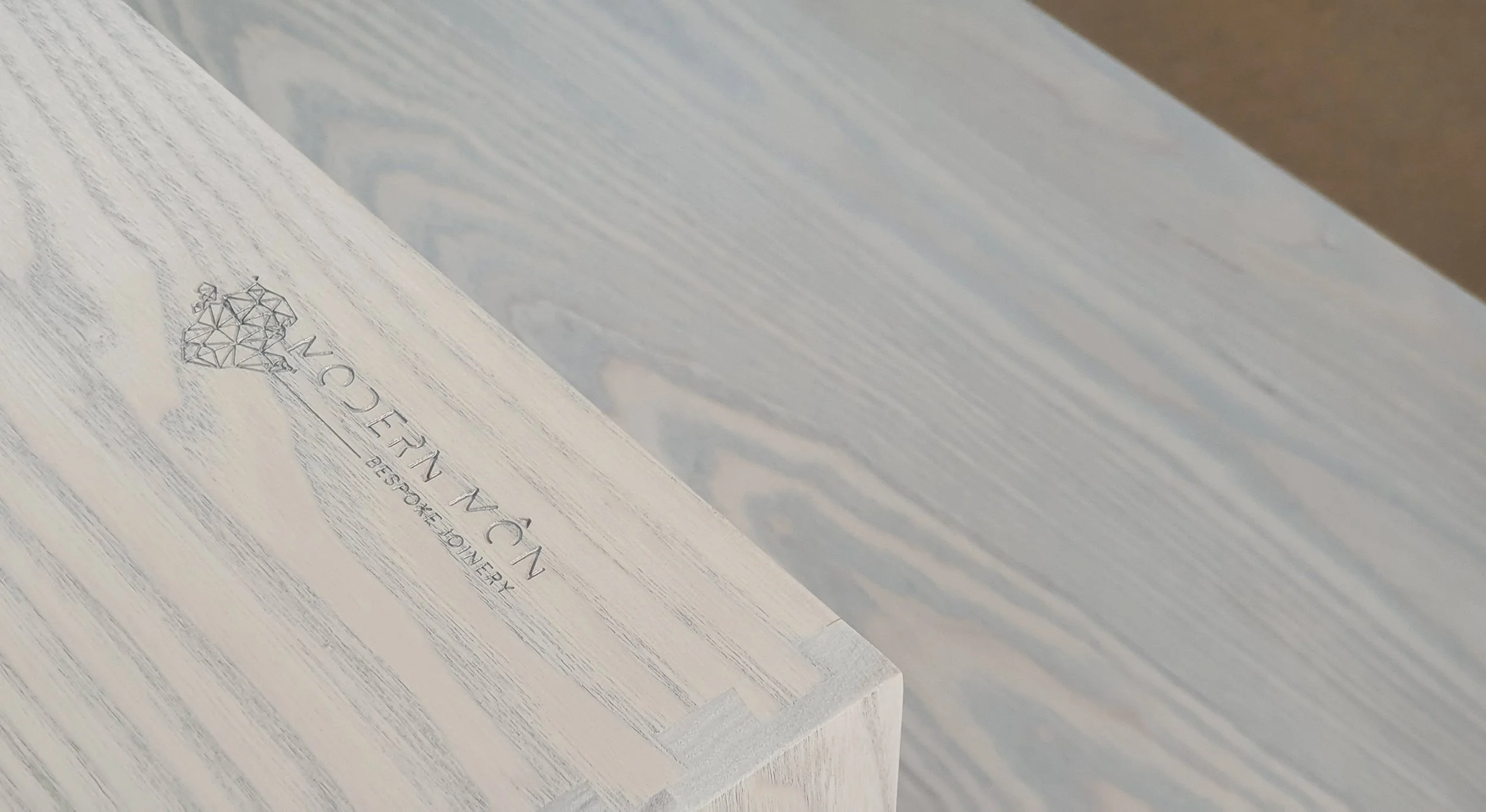 Close-up of a white wood surface with a logo and text engraved, reading "INCONCEIVABLE DESTINATION" and featuring a geometric heart design.