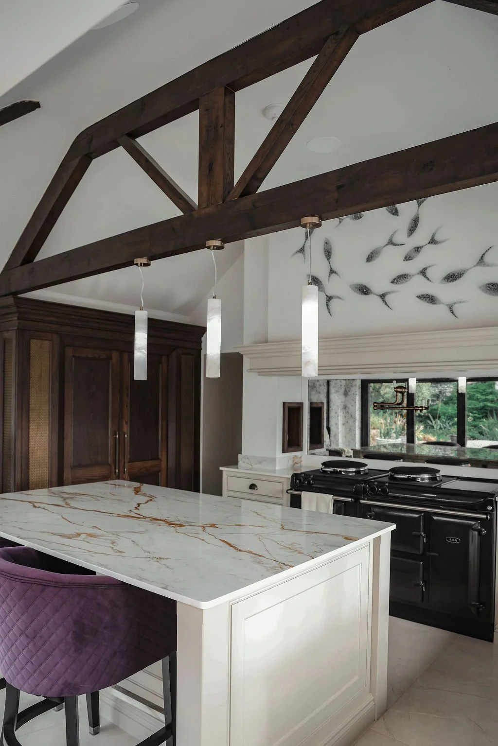 Kitchen with a white marble island, black stove, dark wooden cabinetry, and wall art of fish.