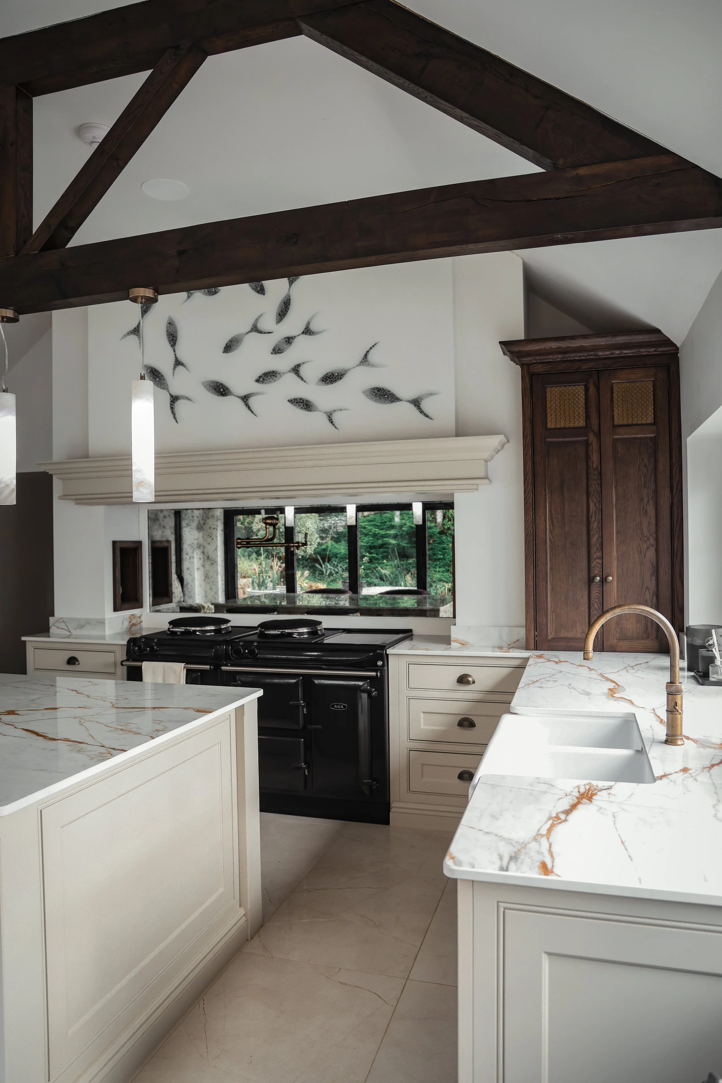 Kitchen with white marble countertops, a black stove, a sink with brass faucet, wooden cabinets, and fish wall art.