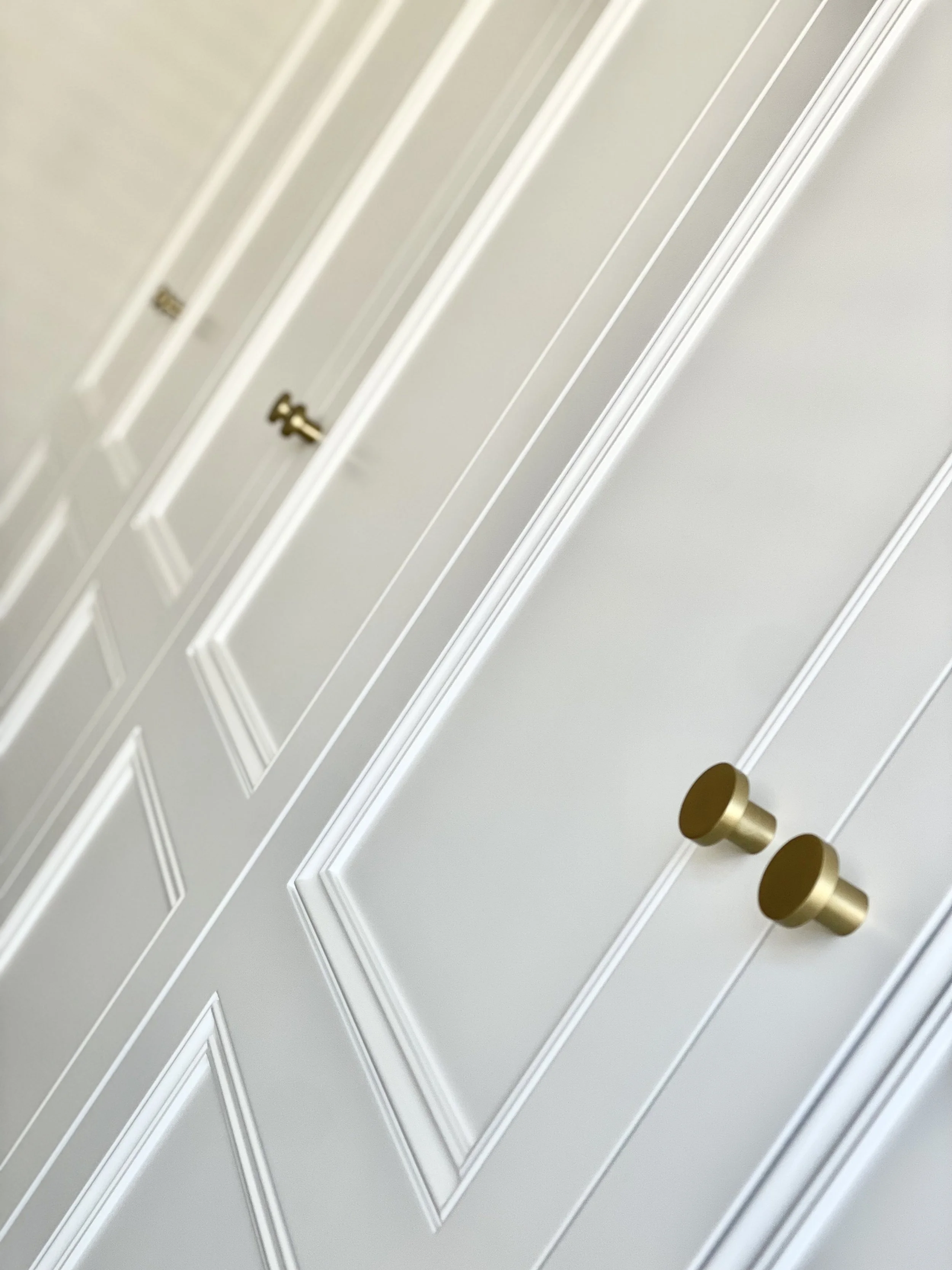 White closet doors with gold knobs.