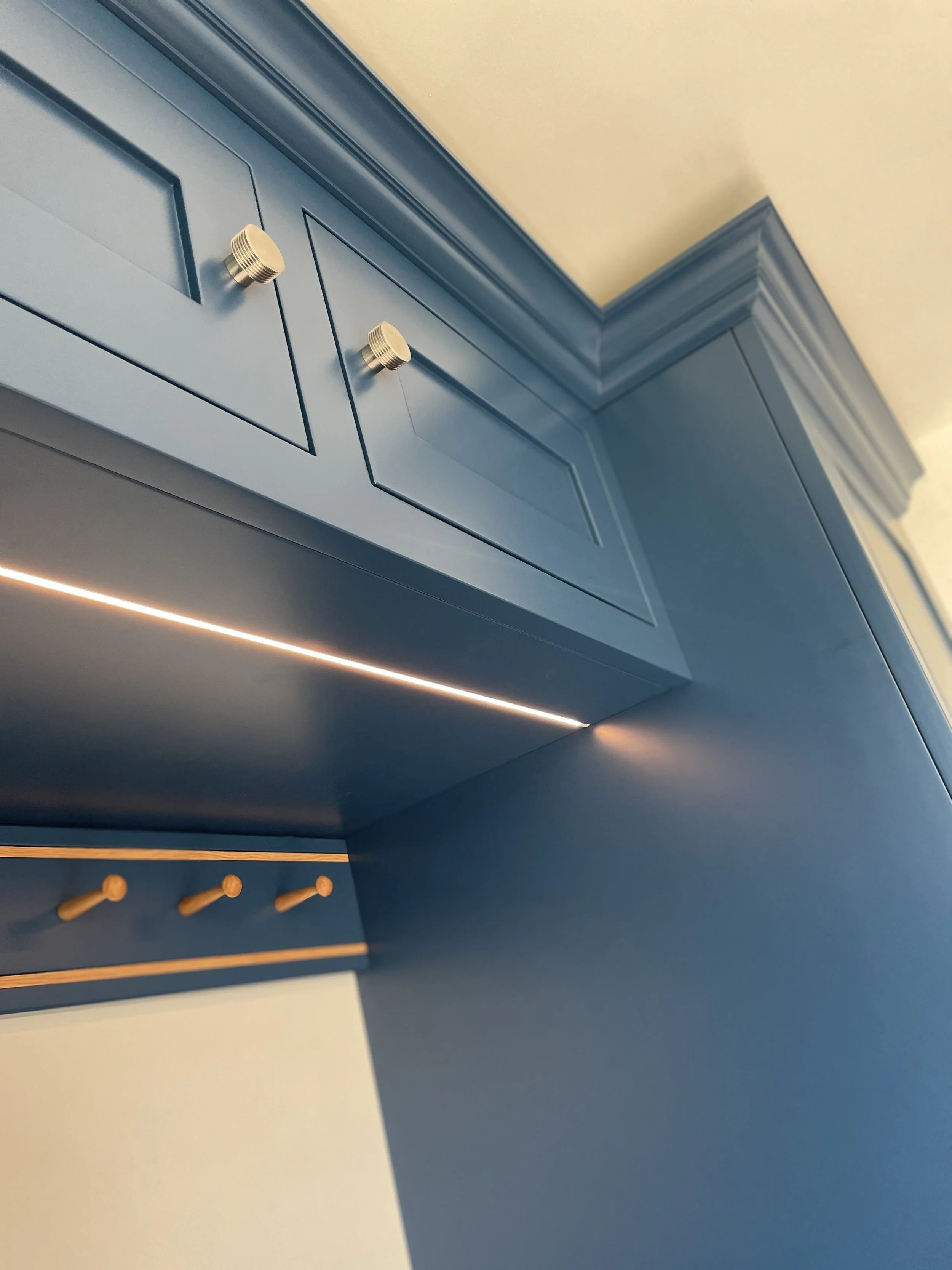 Blue kitchen cabinet with gold knobs and crown molding, taken from a low angle.