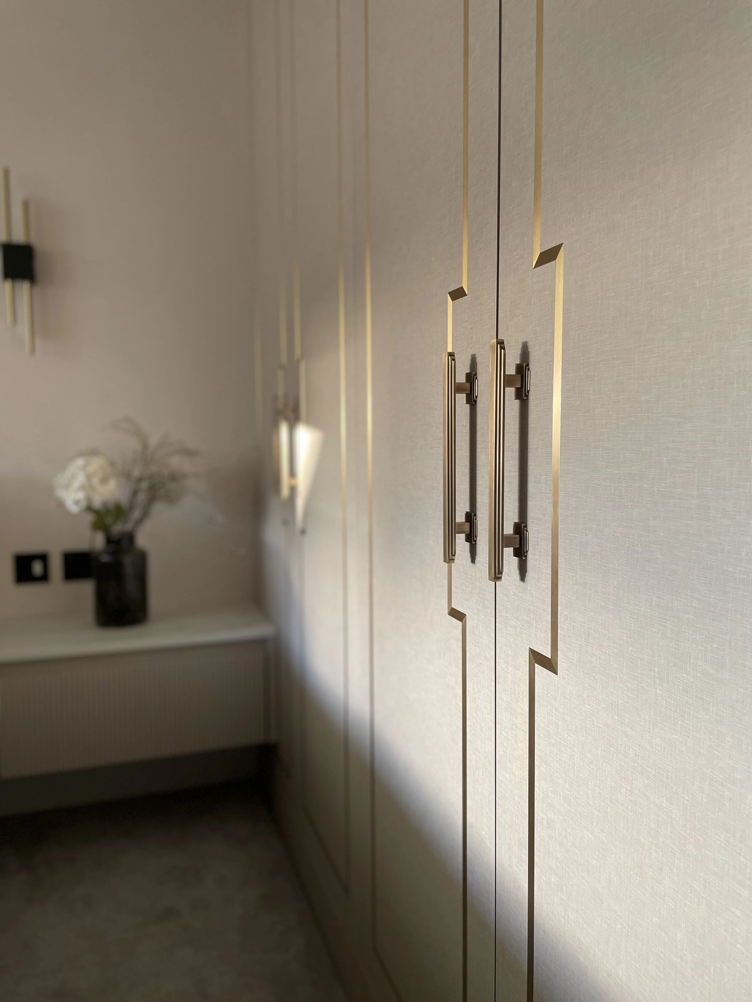 Close-up of beige closet doors with gold trim and handles, part of a modern bedroom interior.