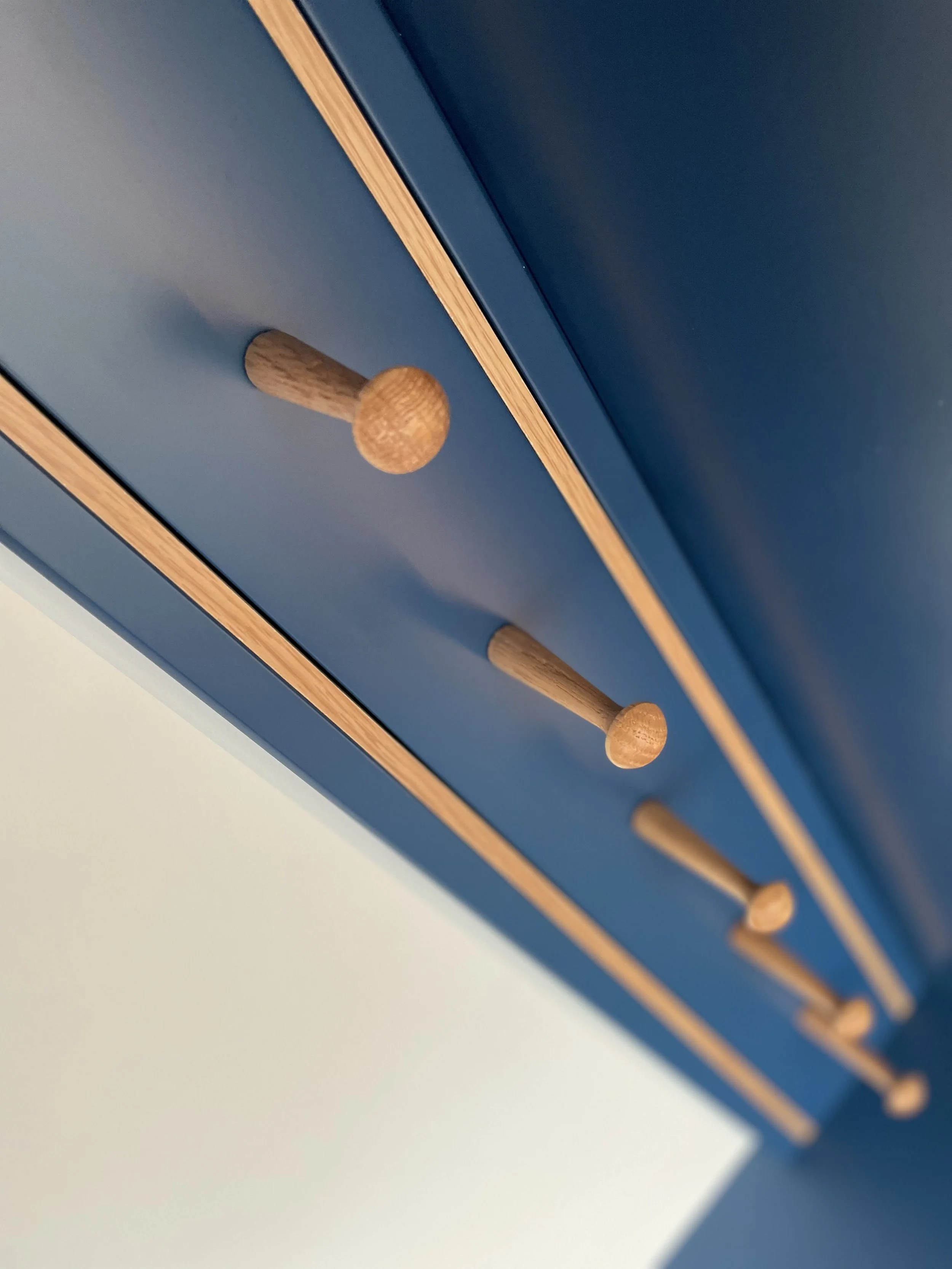 Close-up of a blue cabinet door with four wooden knobs arranged in a diagonal line.