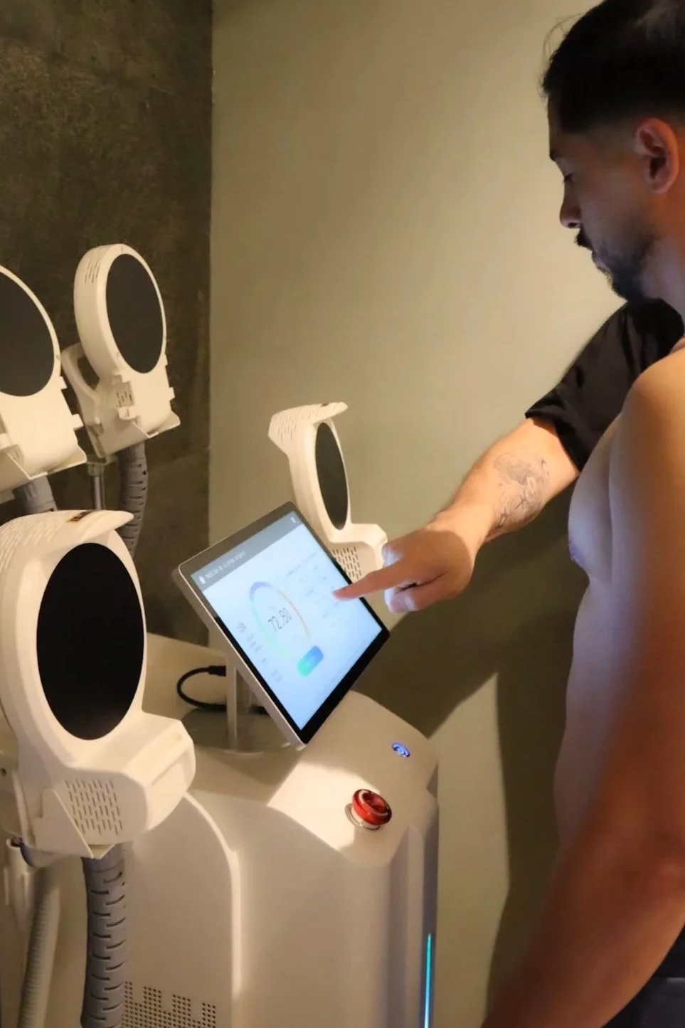 Hombre usando una máquina de fraudes con pantalla táctil en un gimnasio o institución de salud, rodeado de otros equipos de ejercicio.