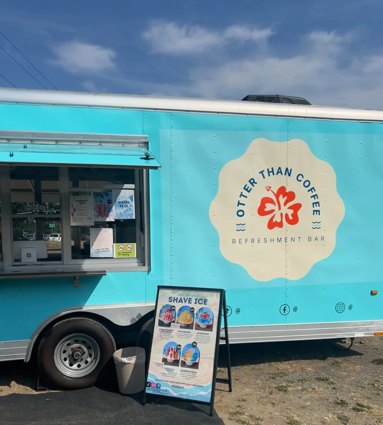 Blue food truck with pastel yellow logo reading 'Otter Than Coffee' and 'Refreshment Bar' on side, menu board for shave ice flavors in front, set outdoors under a partly cloudy sky.