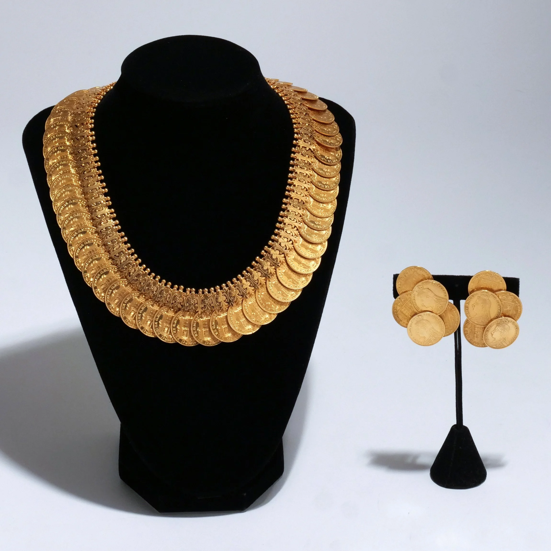 (3pc) 18K GOLD SOVEREIGN DEMI PARURE 
Comprising an articulated necklace of overlapping coins and matching cluster ear clips, 294.4 grams total weight 
$30,000-40,000