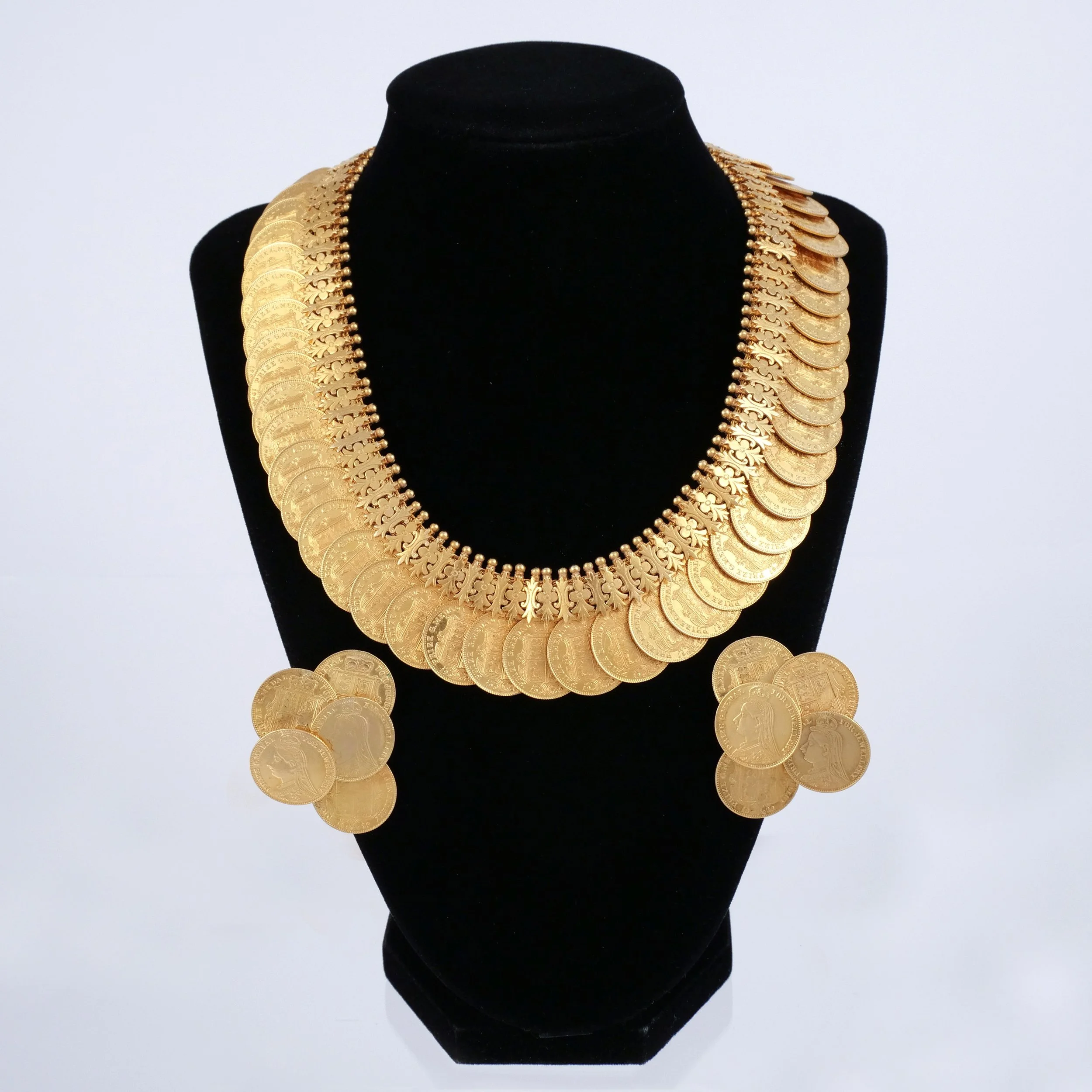 (3pc) 18K & 22K GOLD COIN NECKLACE AND EARRINGS 
Comprising an articulated necklace of overlapping replica coins and matching cluster ear clips, 294.4 grams total weight 
$30,000-40,000