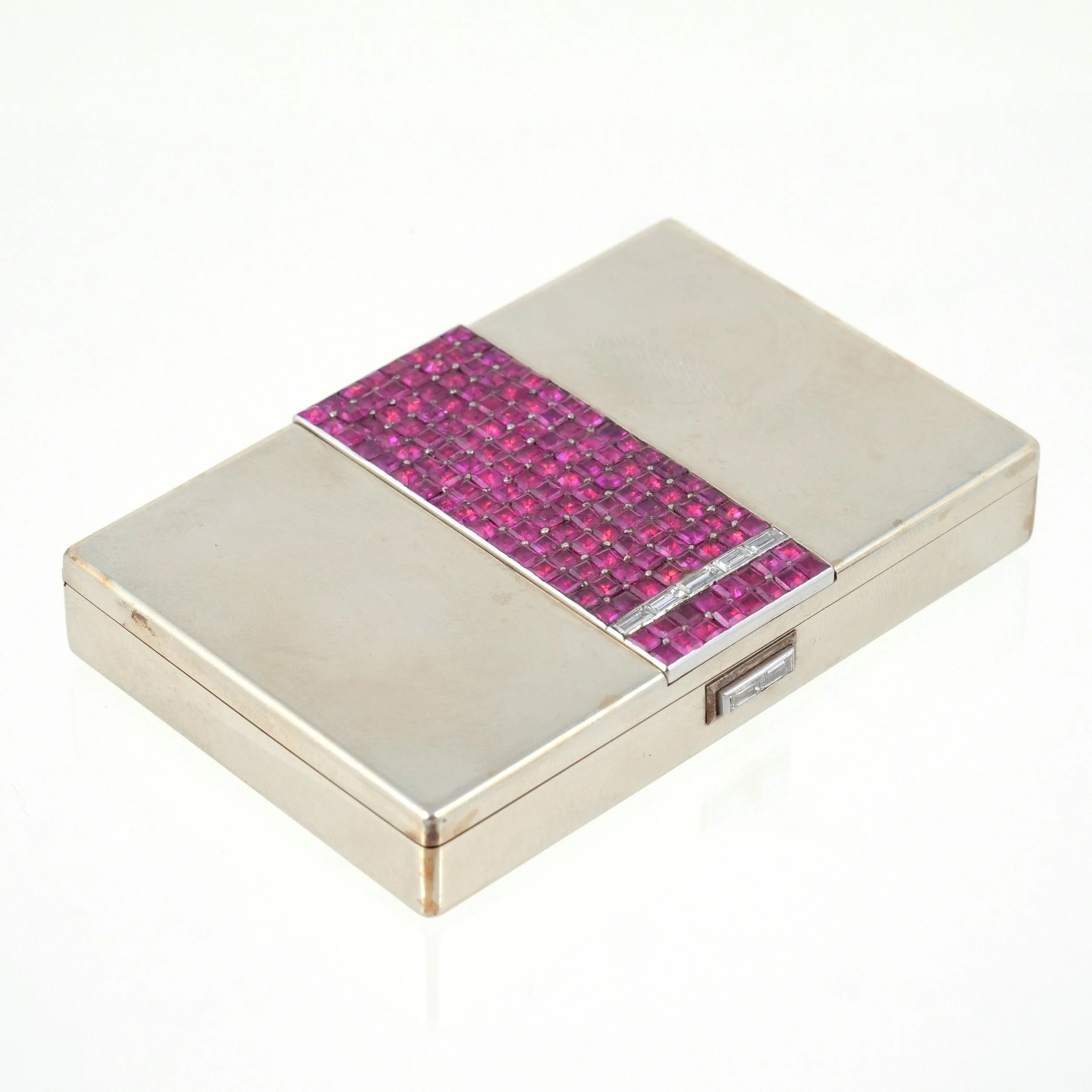 FRENCH 18K WHITE GOLD LADY'S COMPACT 
Art Deco, circa 1920s, with a band of faceted square cut rubies and a strip of diamond baguettes, 180g total 
$20,000-30,000