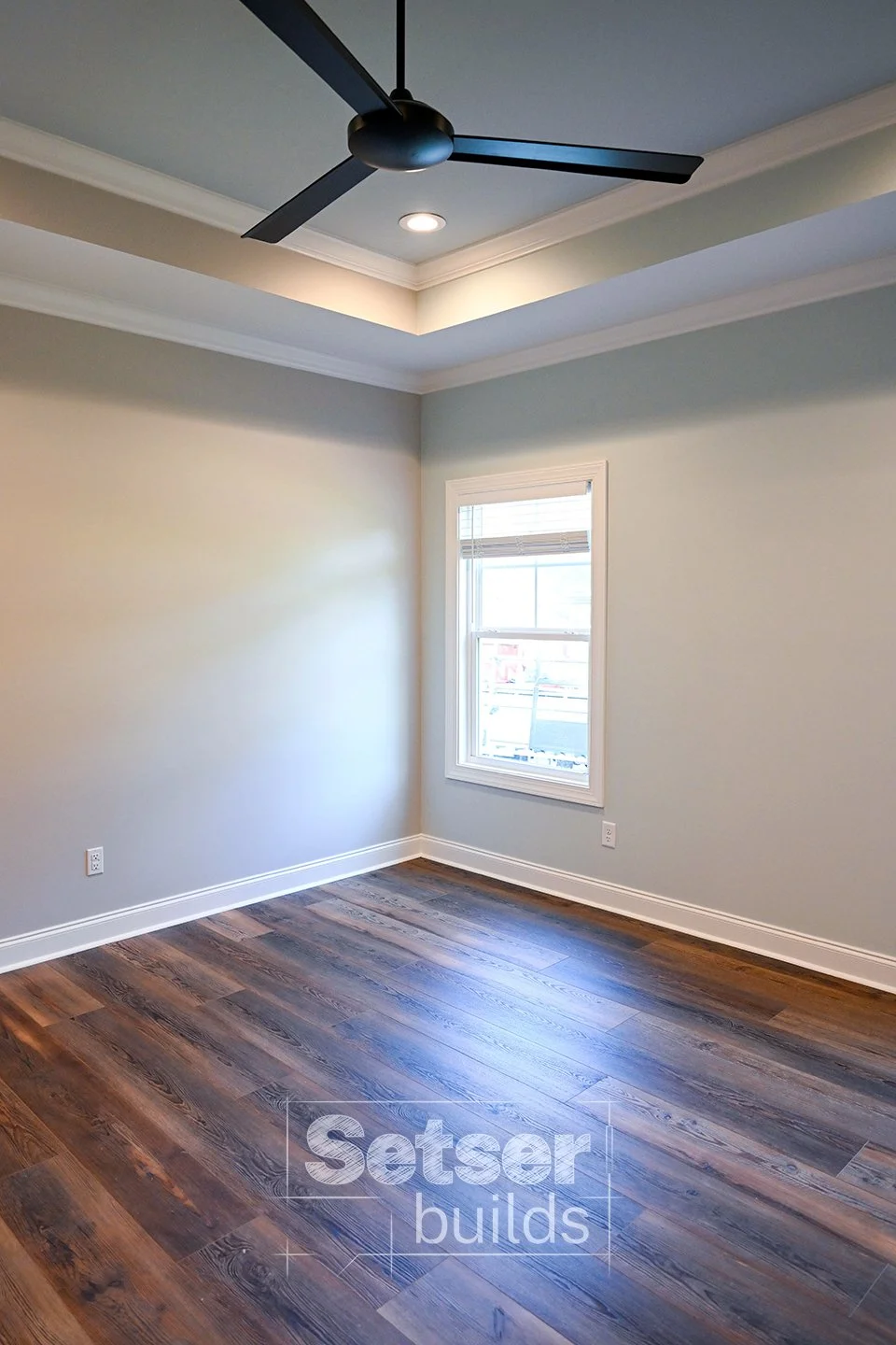 Empty room with hardwood floors, a window, a ceiling fan, and crown molding.