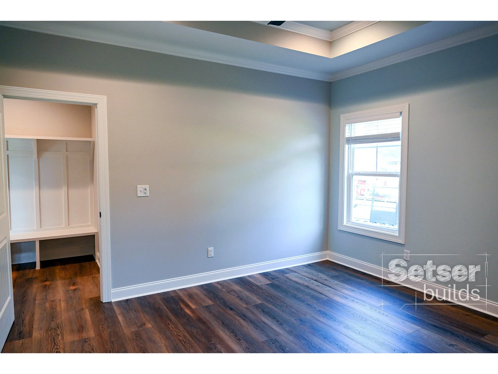 Empty room with hardwood floors, a window, and a small built-in closet.
